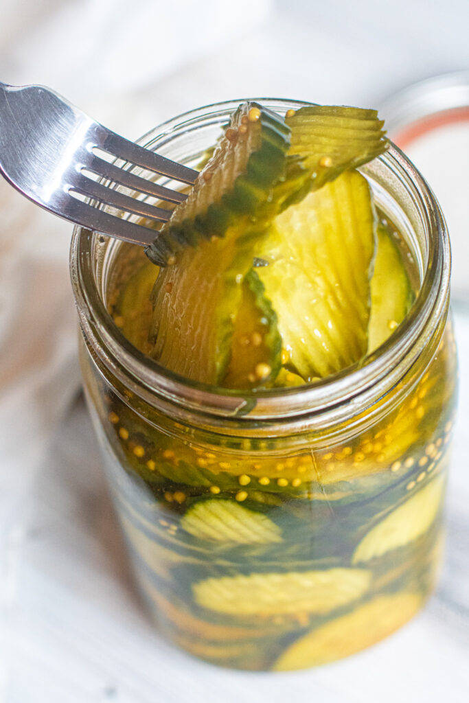 Pickle 桌布 壁紙 — 一個玻璃罐的特寫，裡面裝滿了鹽水蒔蘿泡菜和芥末籽，叉子正挑起一片。