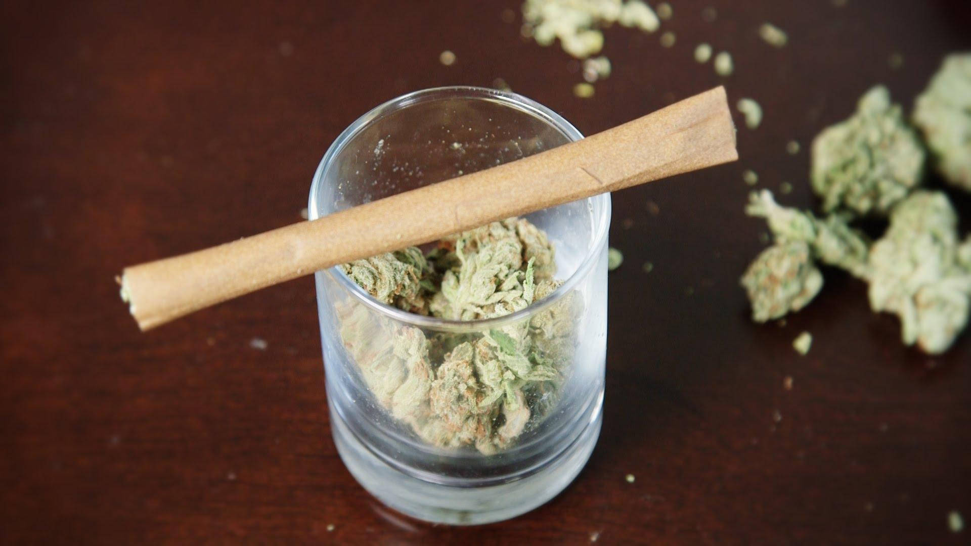 Blunt 桌布 壁紙 — 一個玻璃罐裝滿綠色大麻花蕾，上面放著一根捲好的大麻煙，放在深色木質表面上。