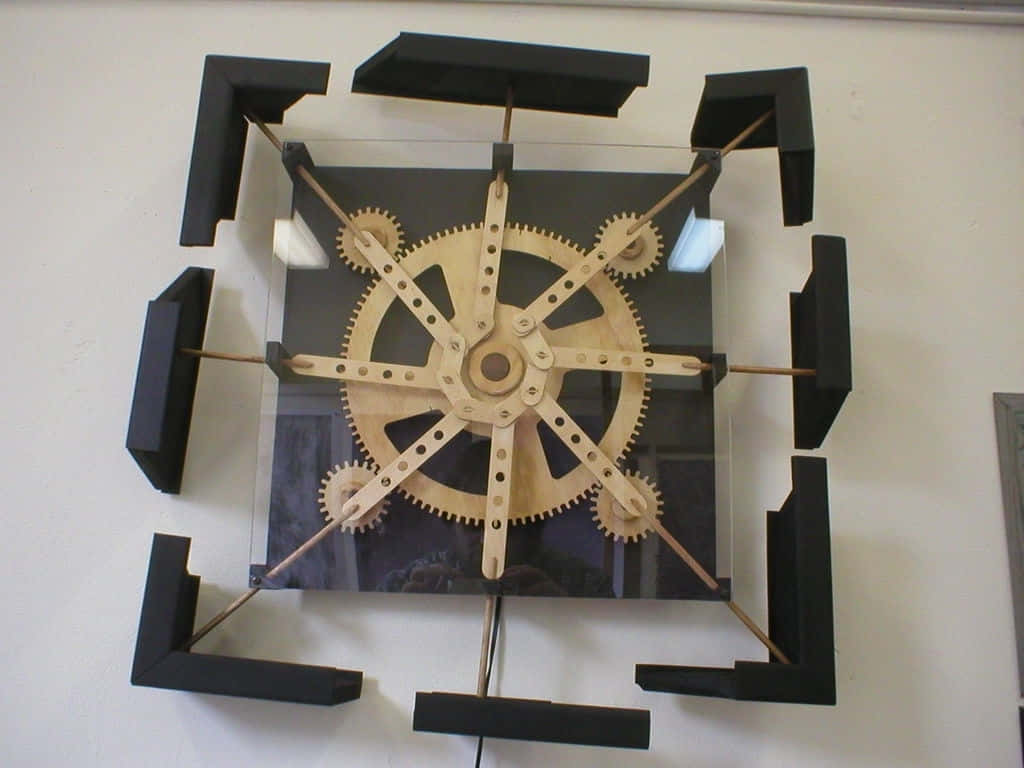Kinetic Art 桌布 壁紙 — 一個現代壁鐘，帶有外露的木齒輪和黑色幾何框架，安裝在純白牆上。