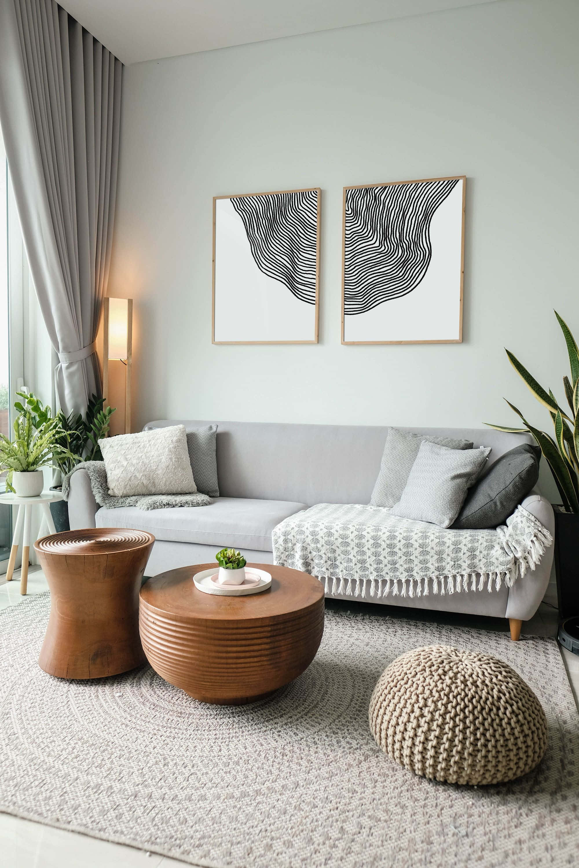 Minimalist Design 桌布 壁紙 — 一個現代客廳，配有灰色沙發、木製咖啡桌和抽象牆藝，沐浴在柔和自然光中。