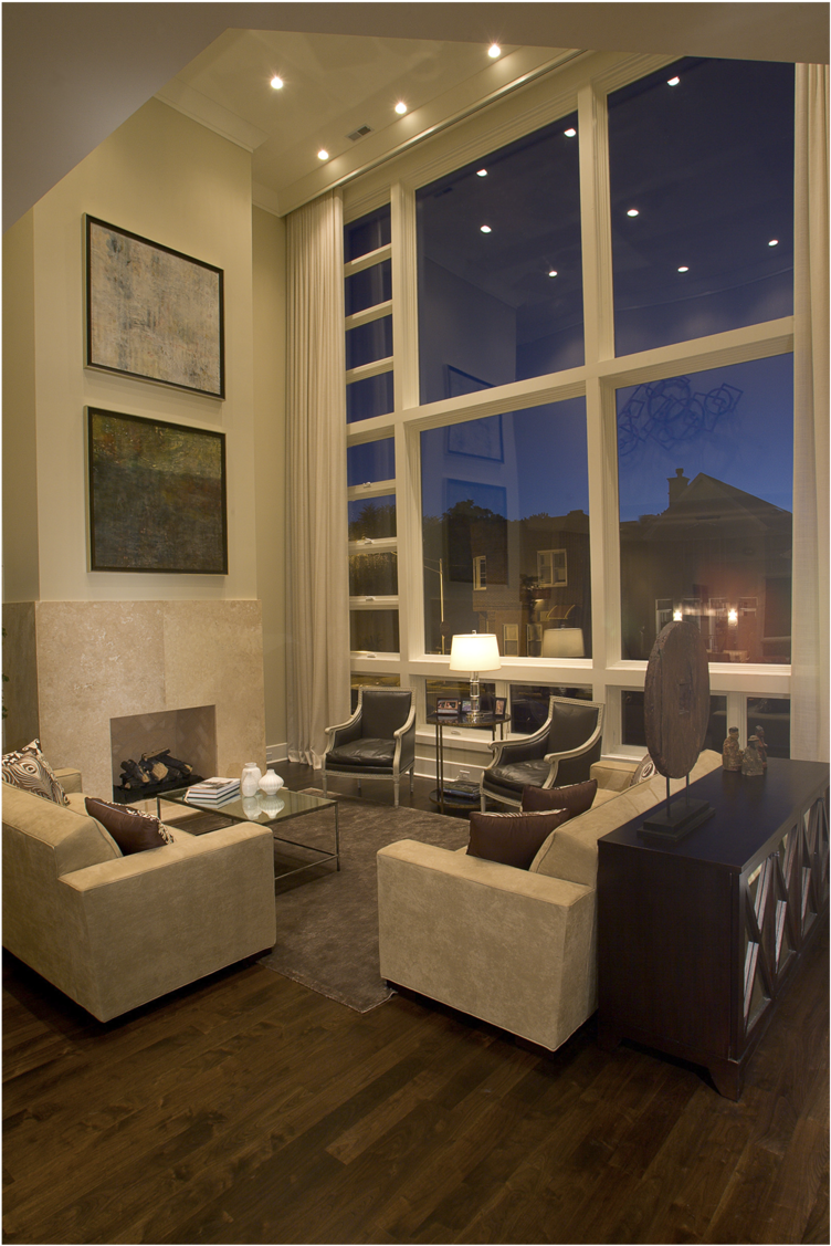 Living Room 桌布 壁紙 — 一個現代客廳，配有米色沙發、深色木地板和展示暮色城市景觀的大窗戶。