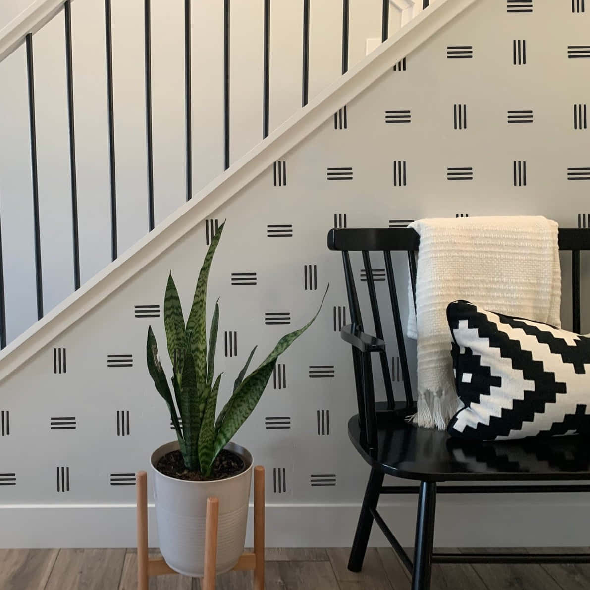 Interior Design 桌布 壁紙 — 一個現代室內角落，配有黑色椅子、圖案壁紙和盆栽虎尾蘭，在柔和自然光下。