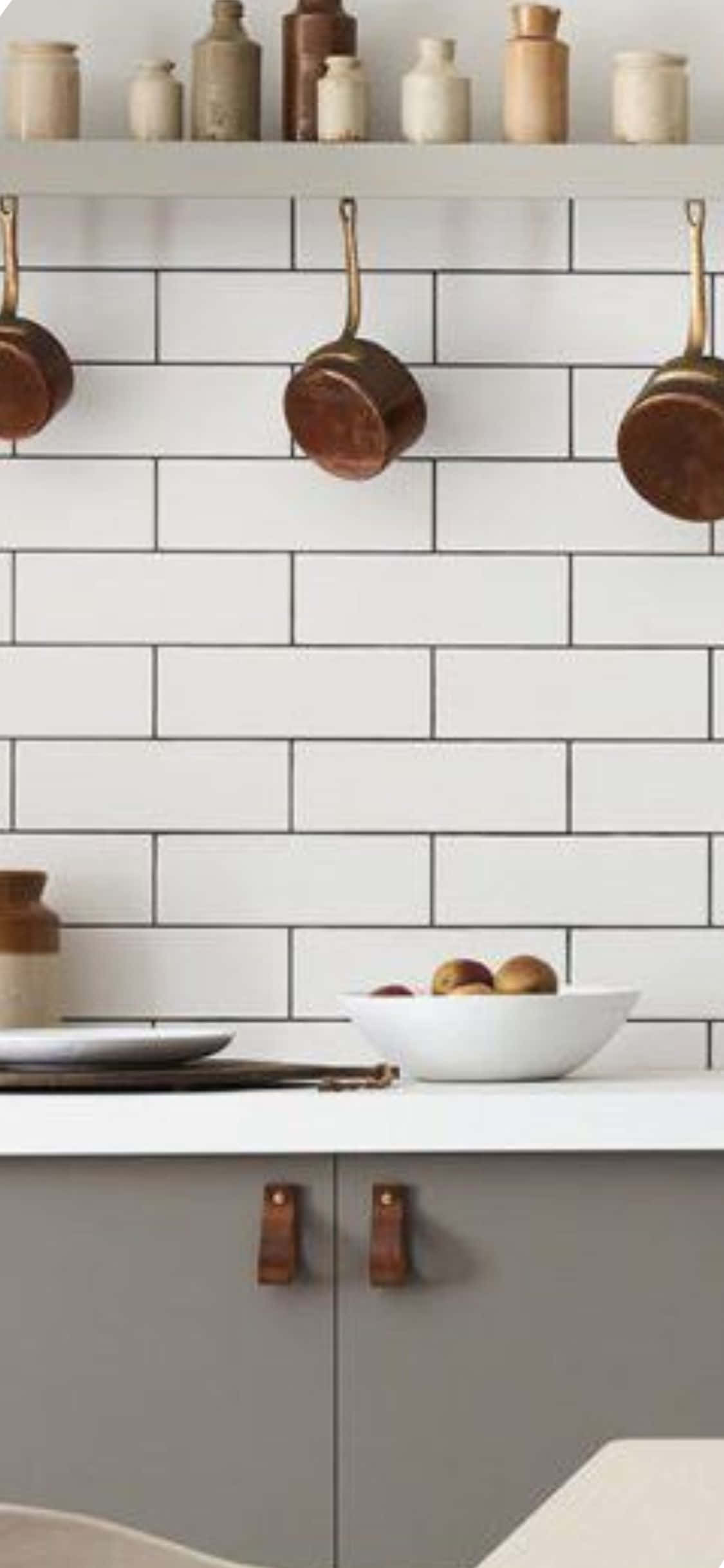 Kitchen Design 桌布 壁紙 — 一個現代廚房，配有白色地鐵磚、灰色櫥櫃和掛在檯面上方帶有水果碗的銅鍋。