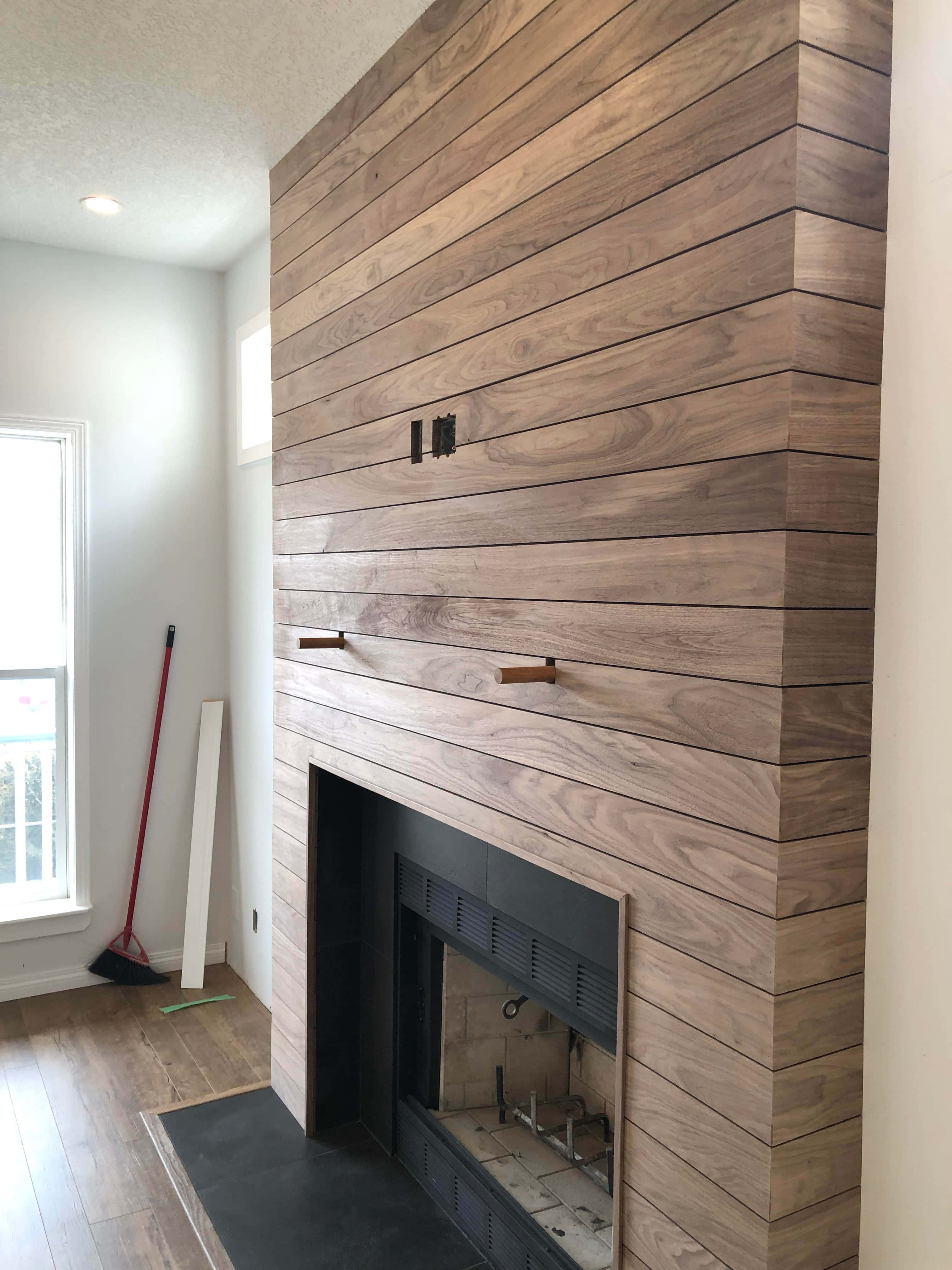 Shiplap 桌布 壁紙 — 一個現代木製壁爐，帶有水平條紋和黑色金屬裝飾，位於明亮的簡約客廳中。