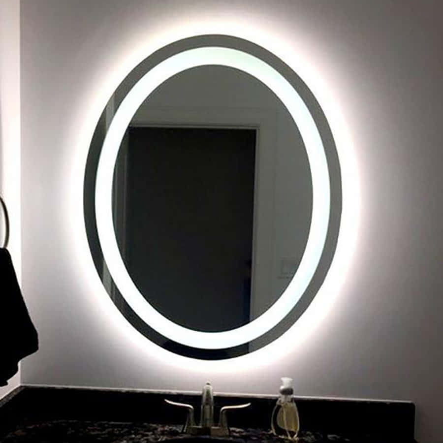mirror 桌布 壁紙 — 一個現代橢圓形鏡子，配有明亮的LED照明，在白色牆壁上發光，位於深色檯面水槽上方。