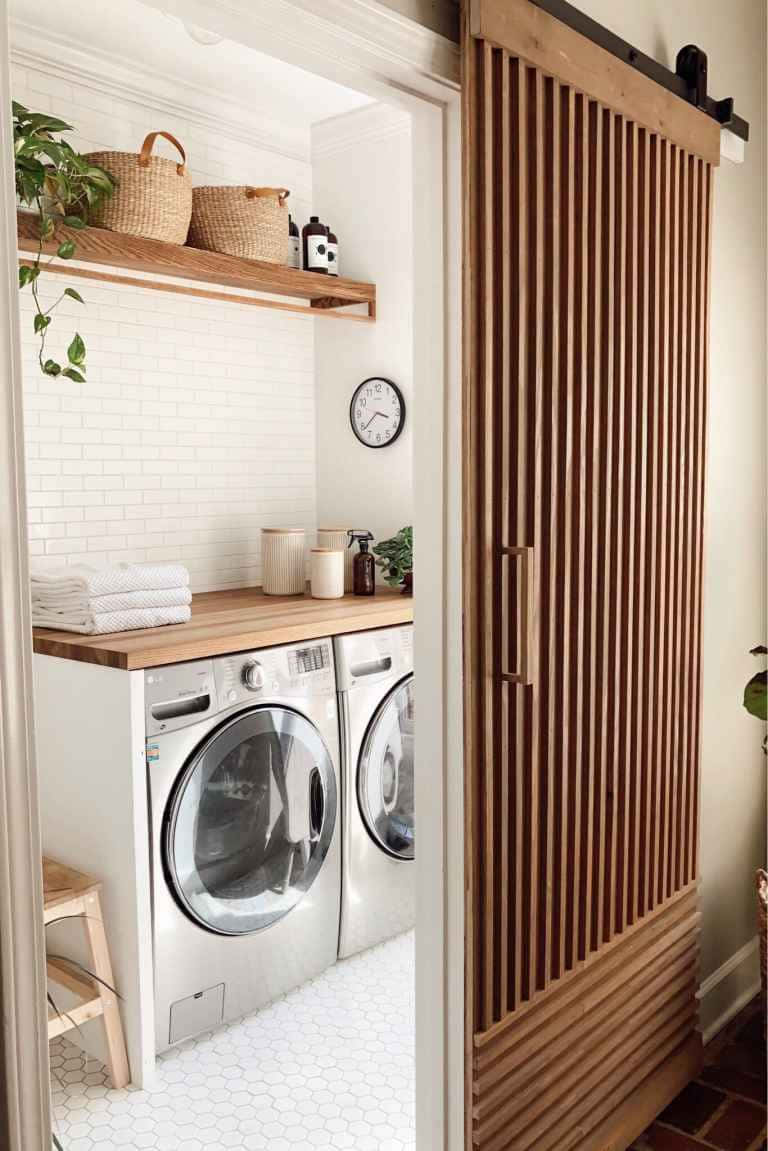 Laundry Room 桌布 壁紙 — 一個現代洗衣房，配有白色地鐵磚、木質層架和條紋木穀倉門。