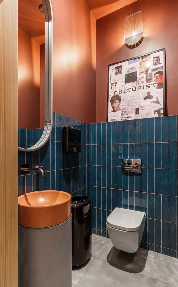 Toilet 桌布 壁紙 — 一個現代浴室，有赤陶牆、藍色瓷磚的下半部分牆壁、一個赤陶洗手盆和牆上一個帶框的雜誌封面。