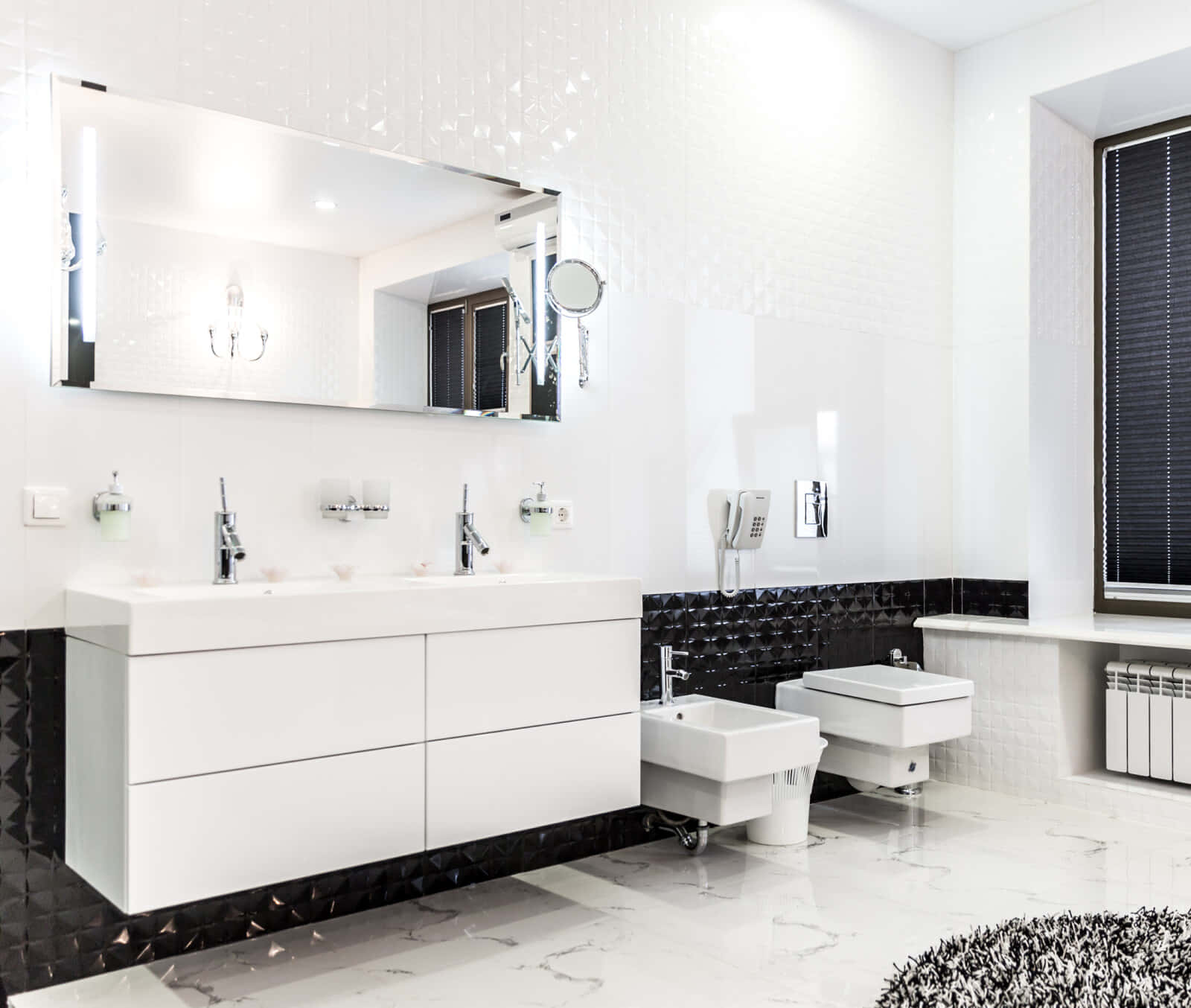 Black And White Bathroom 桌布 壁紙 — 一個現代浴室，配有白色梳妝台、黑色瓷磚點綴和明亮燈光下的大理石地板。