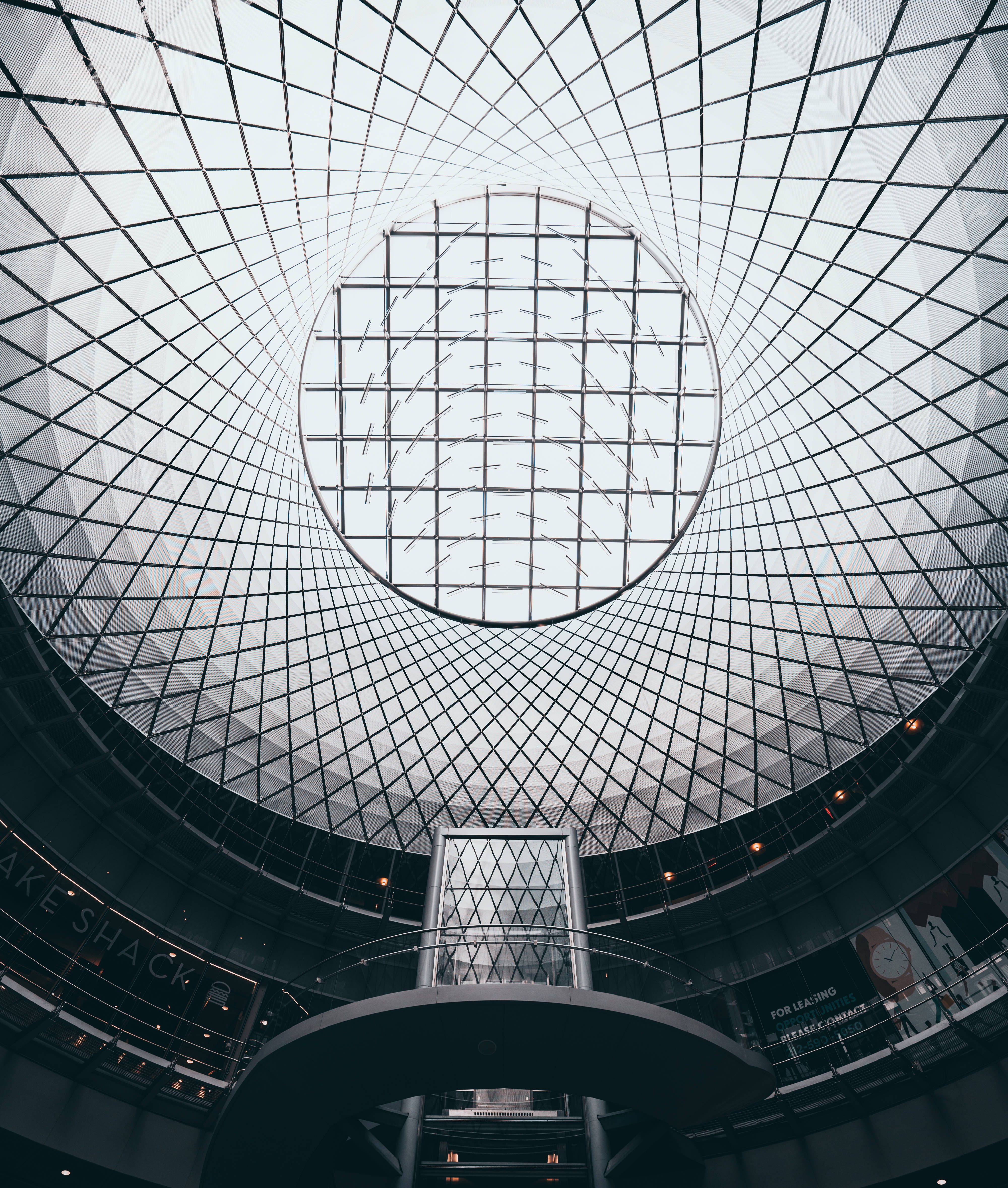 Nyc Aesthetic 桌布 壁紙 — 一個現代玻璃和鋼製圓頂天花板的戲劇性向上視角，帶有幾何圖案和中央圓形天窗。