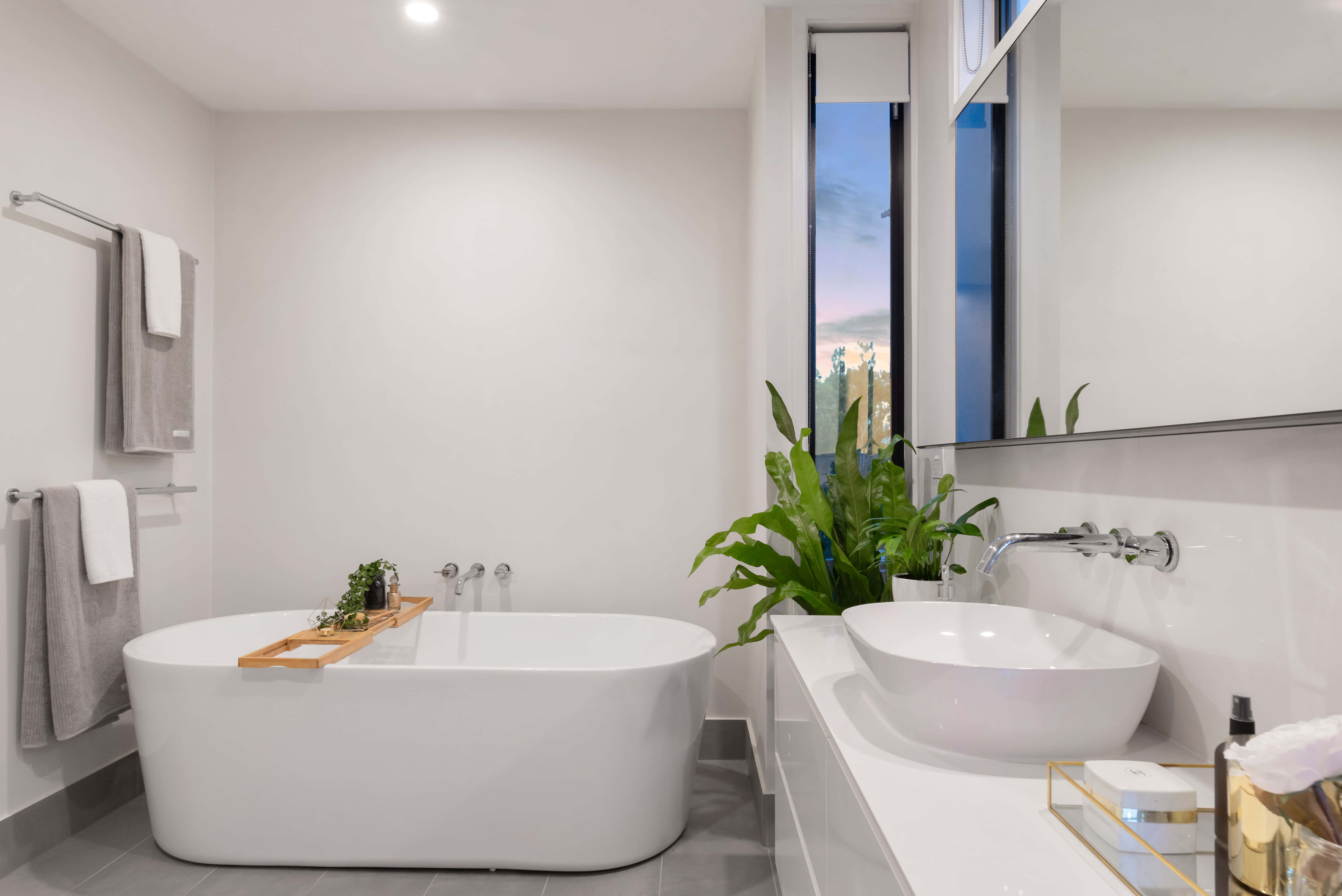 bathroom 桌布 壁紙 — 一個現代簡約浴室，配有獨立式浴缸、時尚白色洗手台，以及可欣賞暮色天空的大窗戶。
