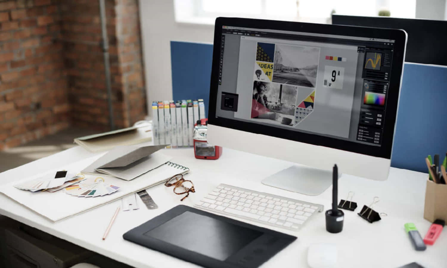 graphic design 桌布 壁紙 — 一個現代設計師的工作站，配備顯示圖形設計工具的電腦和平板電腦，放在白色桌子上，旁邊有顏色樣本和文具。