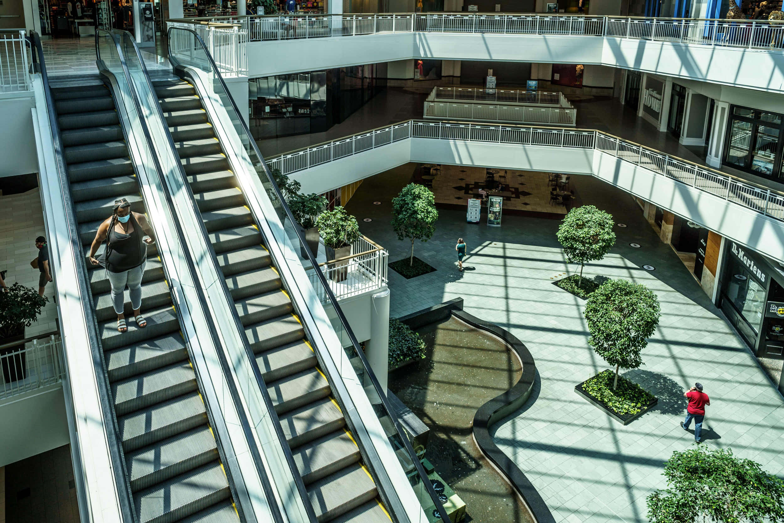 Mall Of America 桌布 壁紙 — 一個現代購物中心的高角度視圖，設有自動扶梯和購物者，在明亮的自然光下。