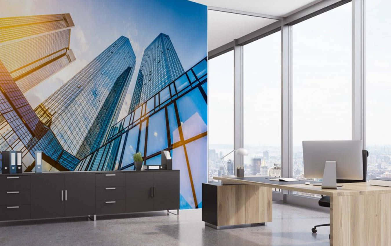 Office Building 桌布 壁紙 — 一個現代辦公室，設有大型玻璃牆，展示在明亮藍天下高聳摩天大樓的活力城市景觀。