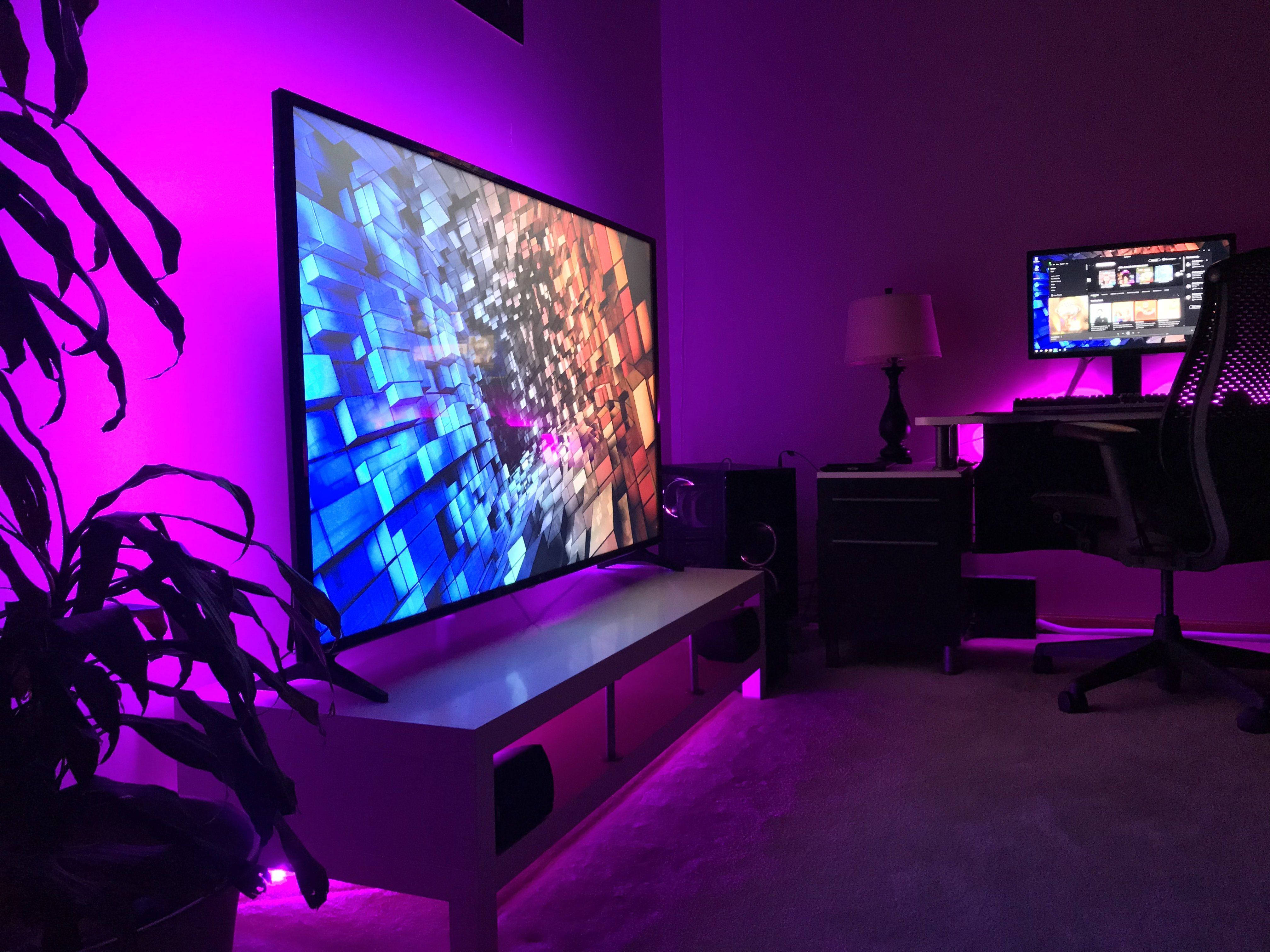 television 桌布 壁紙 — 一個現代遊戲室，沐浴在紫色環境光中，大電視顯示色彩繽紛的抽象立方體動畫。