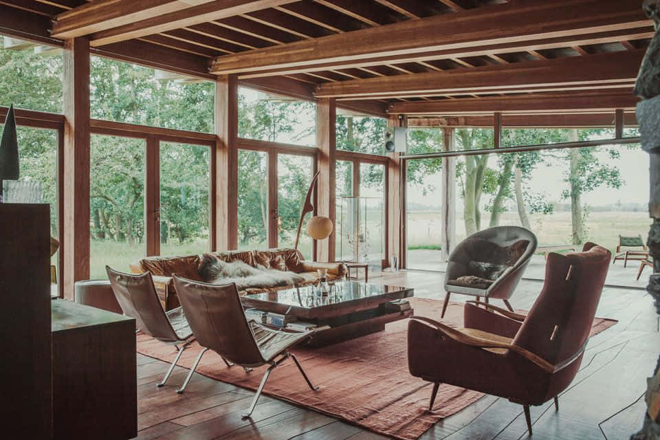 cabin 桌布 壁紙 — 一個現代鄉村風格的客廳，配有木樑和俯瞰綠色田野的大窗戶。