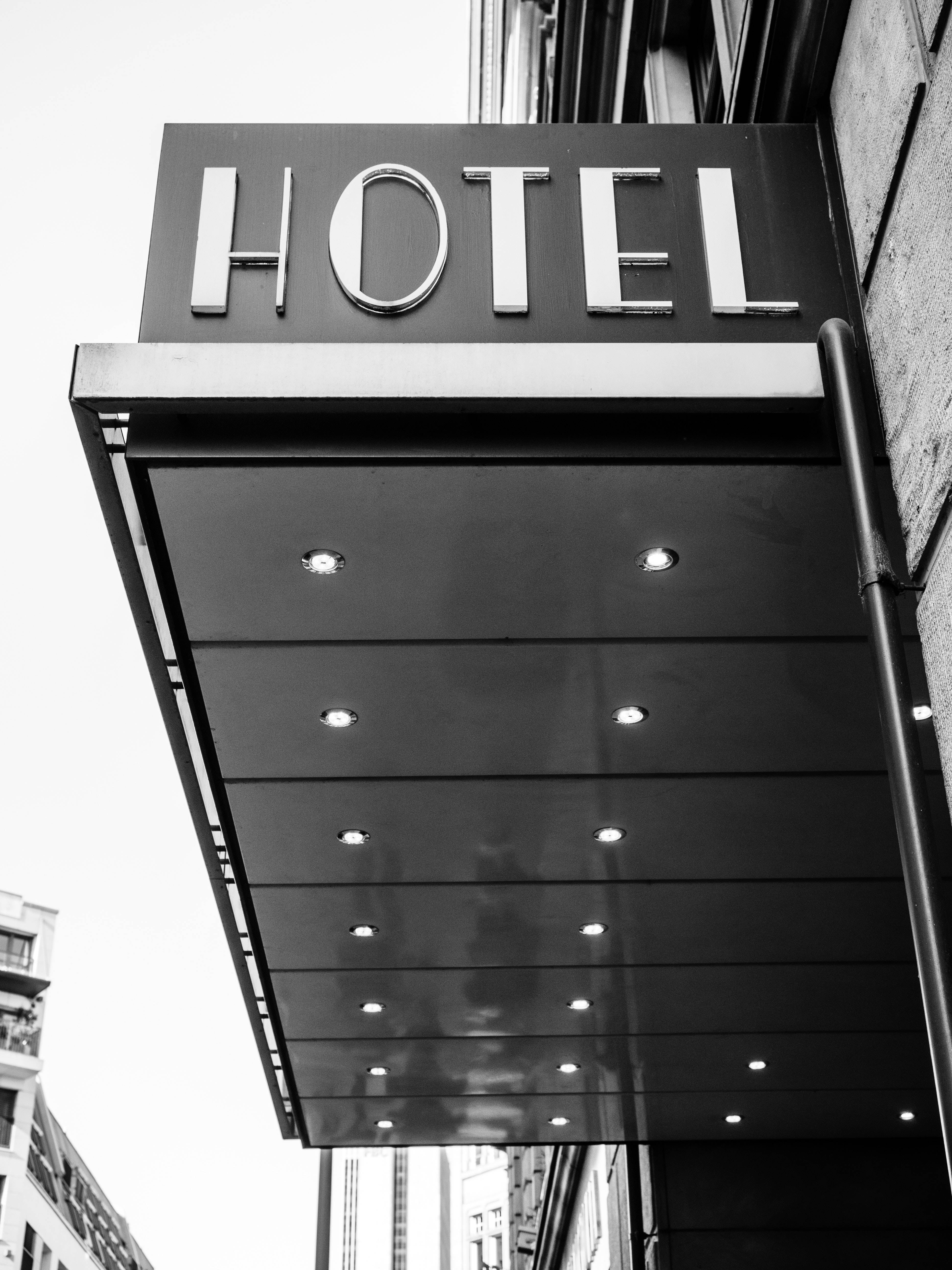 Hotel 桌布 壁紙 — 一個現代酒店招牌在簷篷下帶有嵌入式燈光的鮮明黑白低角度拍攝。