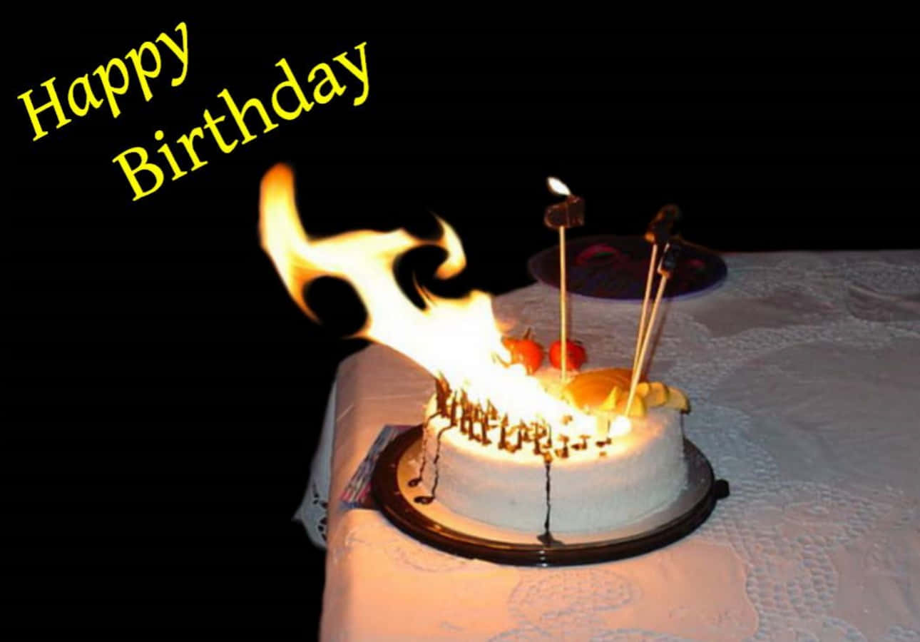 搞笑 桌布 壁紙 — 一個生日蛋糕，上面有燃燒的蠟燭，中央噴出巨大的火焰，放在白色桌布上，背景為黑色。