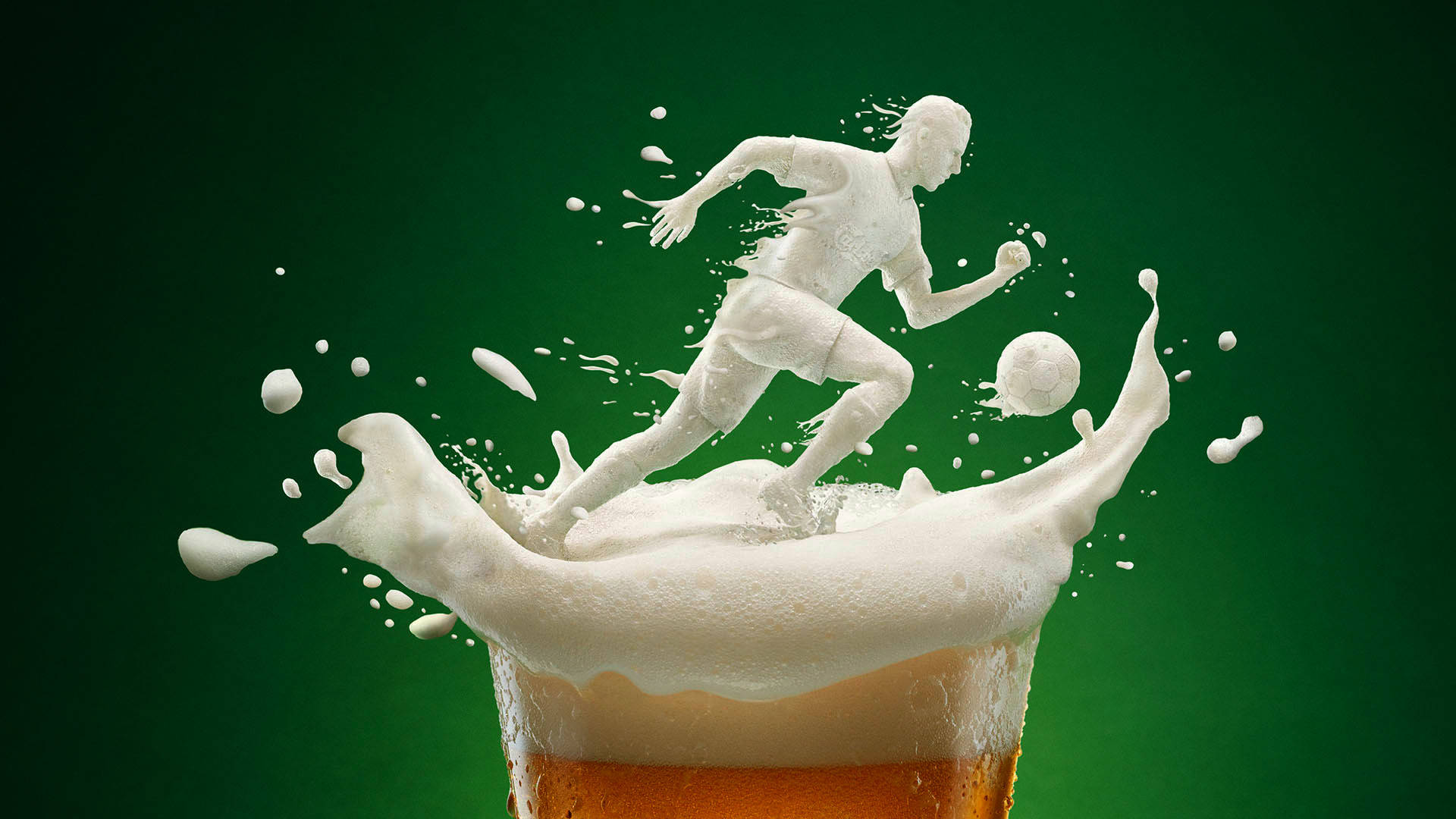 Beer 桌布 壁紙 — 一個用啤酒泡沫雕刻而成的足球員和足球，從玻璃杯中動態躍出，背景是深綠色。