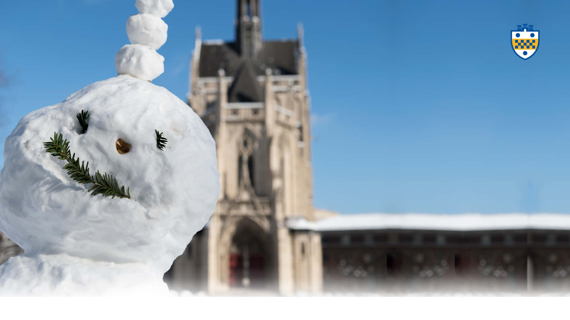 Snow Zoom 桌布 壁紙 — 一個用樹枝做眼睛和嘴巴的快樂雪人，站在晴朗藍天下、積雪的哥德式大教堂前。