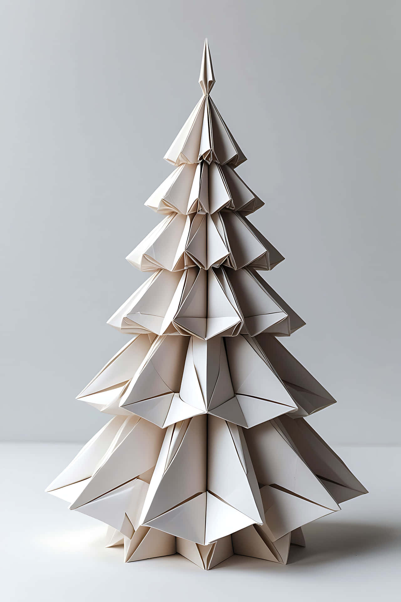 Origami christmas tree 壁紙 — 一個用米色紙製成的極簡摺紙聖誕樹，立在柔和的灰色背景前。