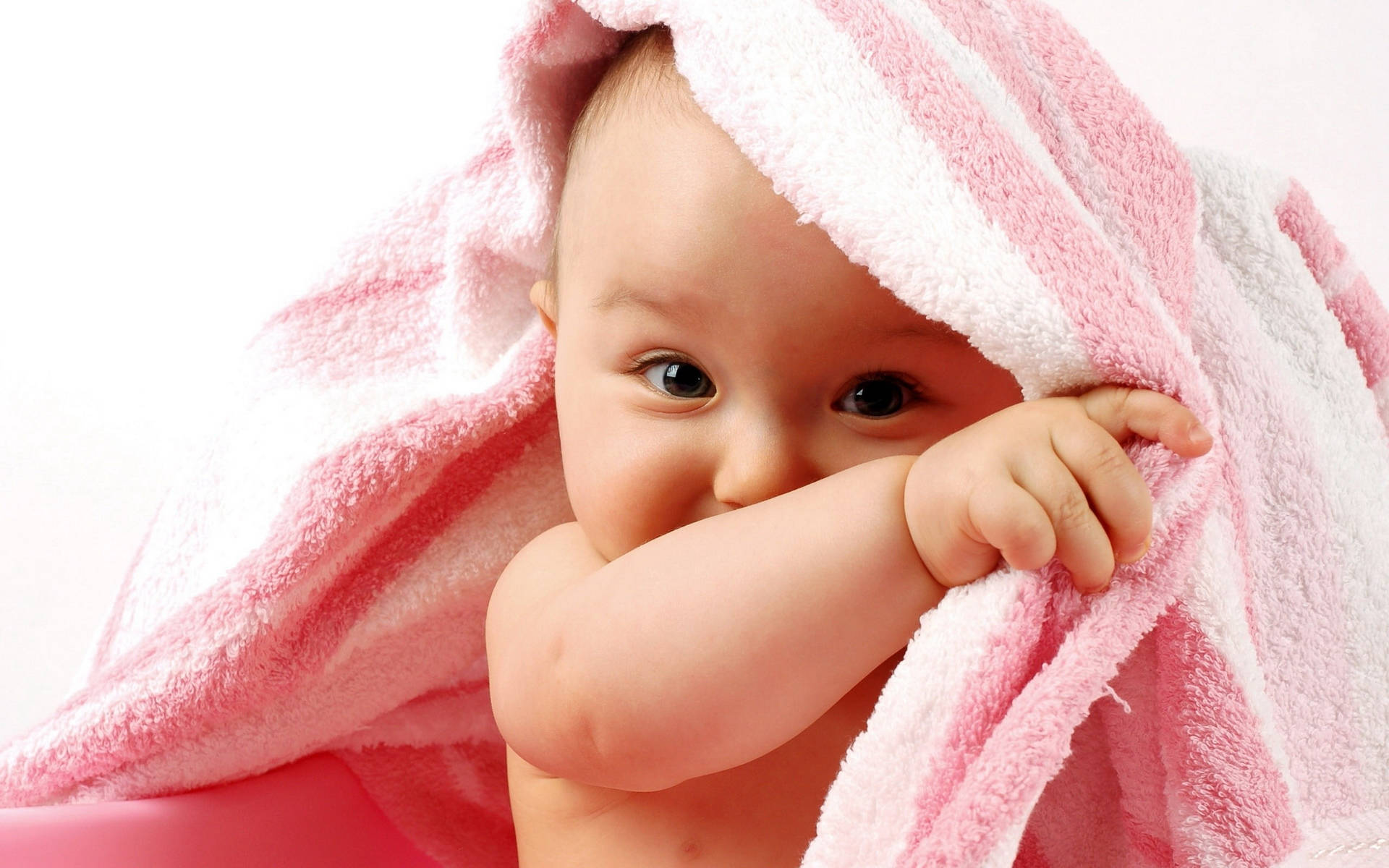 Baby 桌布 壁紙 — 一個用粉紅和白色條紋毛巾包裹的嬰兒，露出好奇的眼睛，同時藏起半張臉。