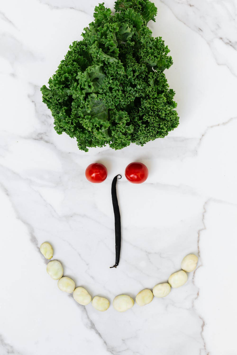 Vegetables 桌布 壁紙 — 一個用羽衣甘藍、櫻桃番茄和白豆在大理石表面上排列而成的開心笑臉。
