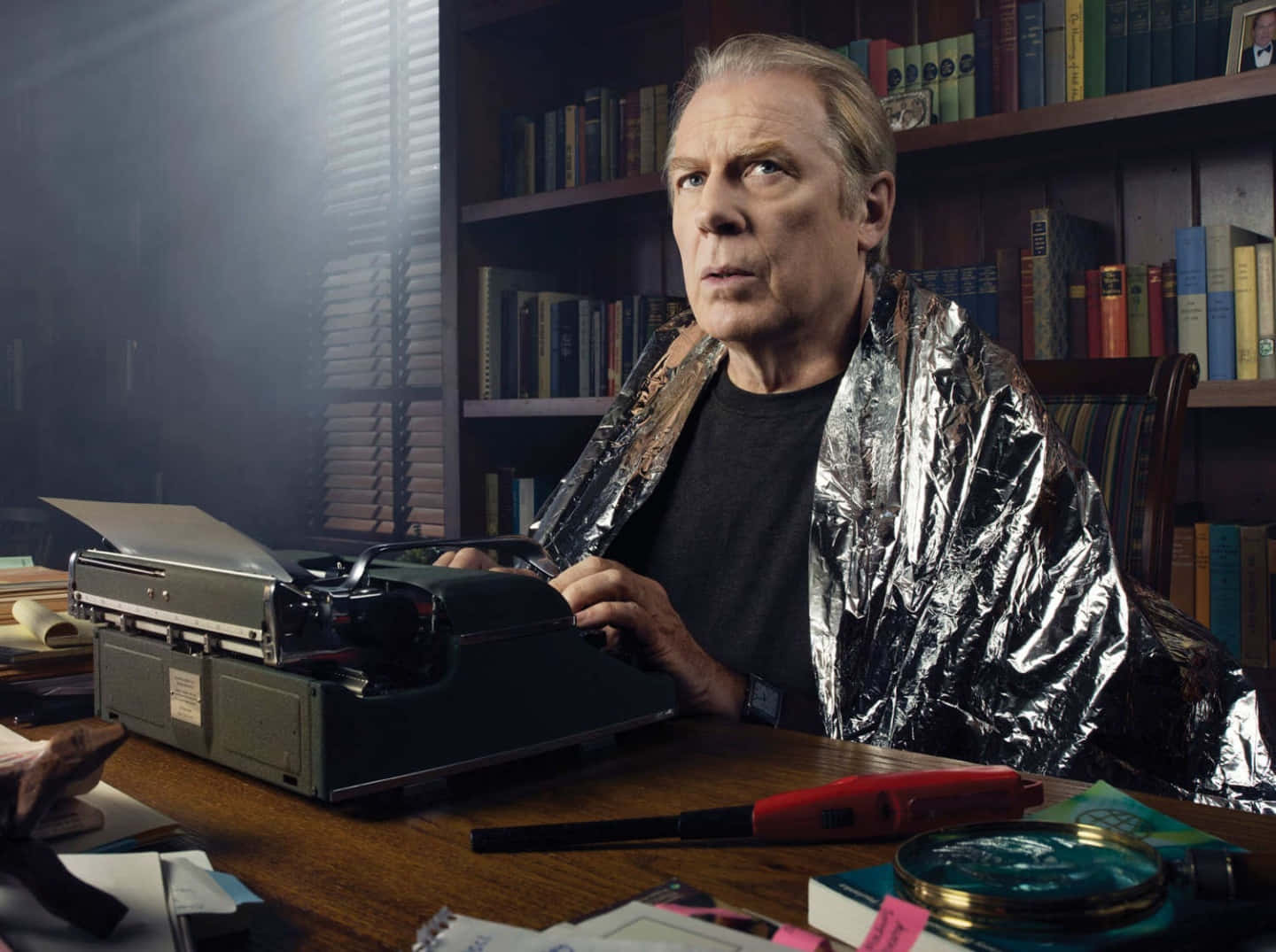 Michael Mckean 桌布 壁紙 — 一個用錫箔紙包裹的男人坐在一張雜亂的書桌前，桌上放著一台復古打字機，房間光線昏暗，到處都是書。