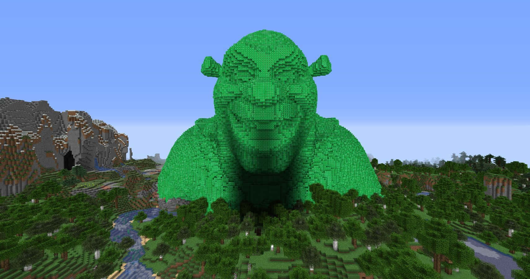 Minecraft Emeralds 桌布 壁紙 — 一個由Minecraft方塊製成的巨大綠色史瑞克，在一片有河流和山脈的森林景觀上空聳立，天空清澈湛藍。