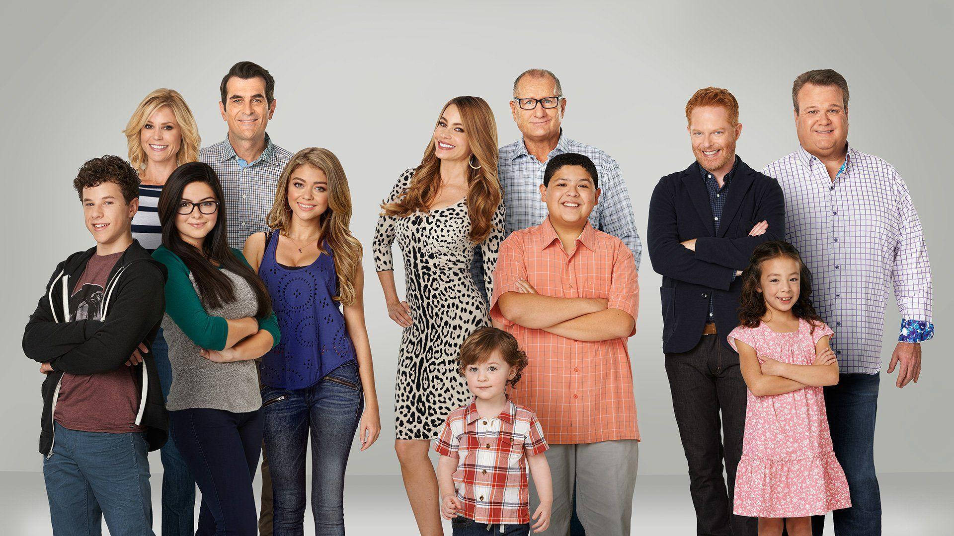Modern Family 桌布 壁紙 — 一個由十人組成的多元大家庭，在純灰色攝影棚背景前自信地交叉雙臂擺姿勢。