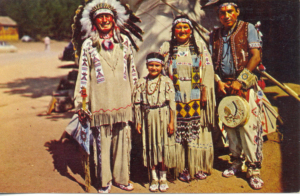 American Indian 桌布 壁紙 — 一個由四名美洲原住民組成的家庭，穿著傳統儀式服裝，在明亮的陽光下於戶外擺姿勢。