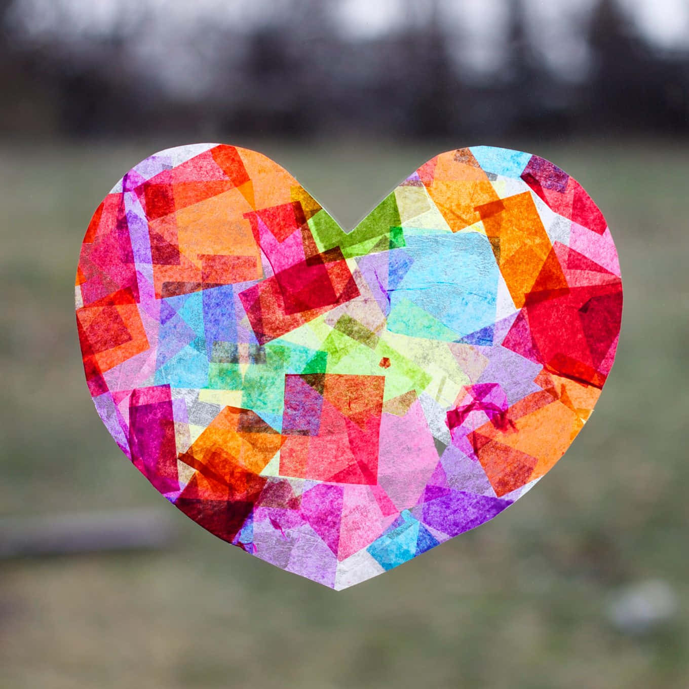 Heart Art 桌布 壁紙 — 一個由彩色半透明正方形製成的鮮豔心形彩繪玻璃窗，懸掛在模糊的戶外背景前。