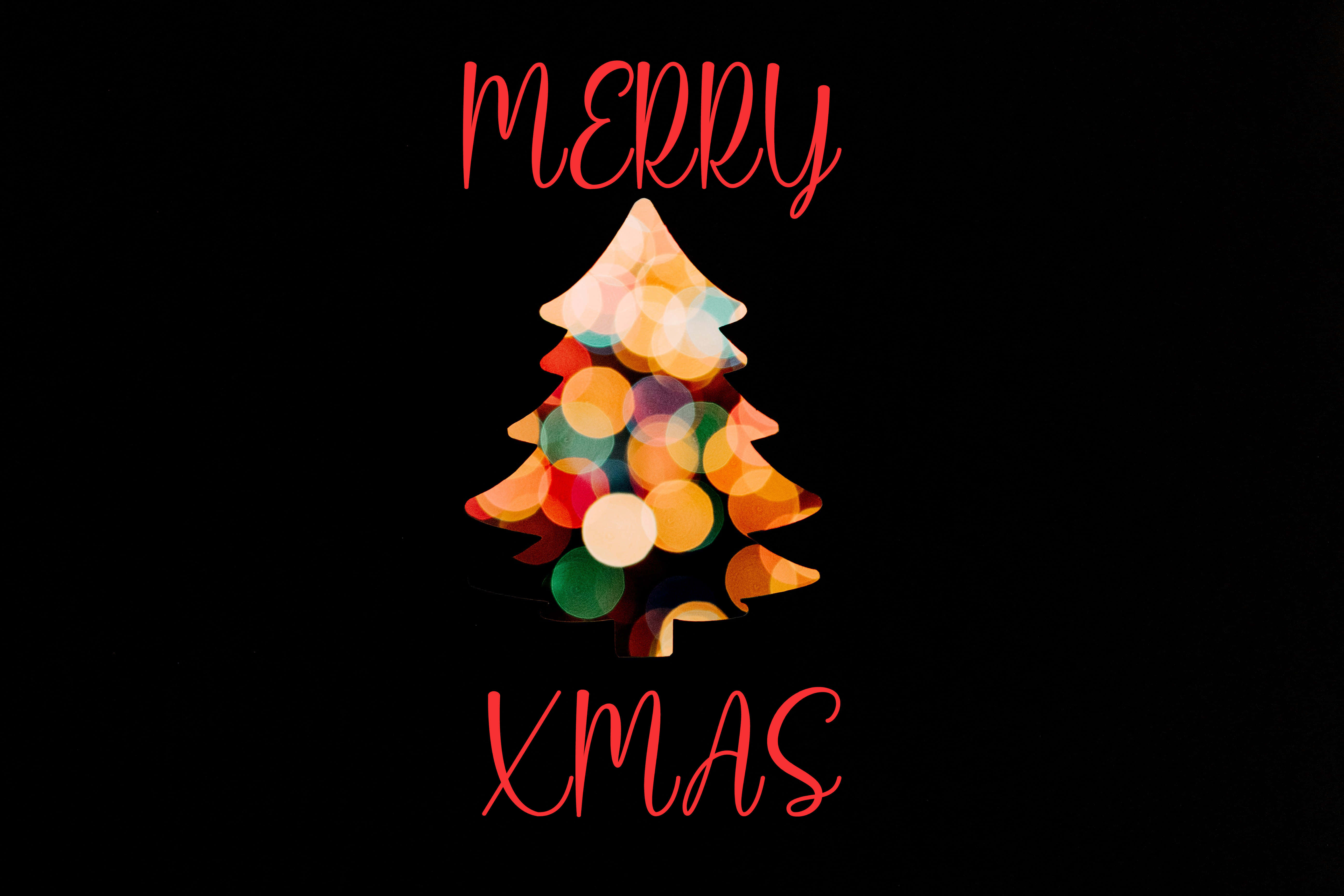 Festive 桌布 壁紙 — 一個由彩色散景燈光組成的節日聖誕樹，居中於黑色背景上的紅色斜體「MERRY XMAS」文字之間。