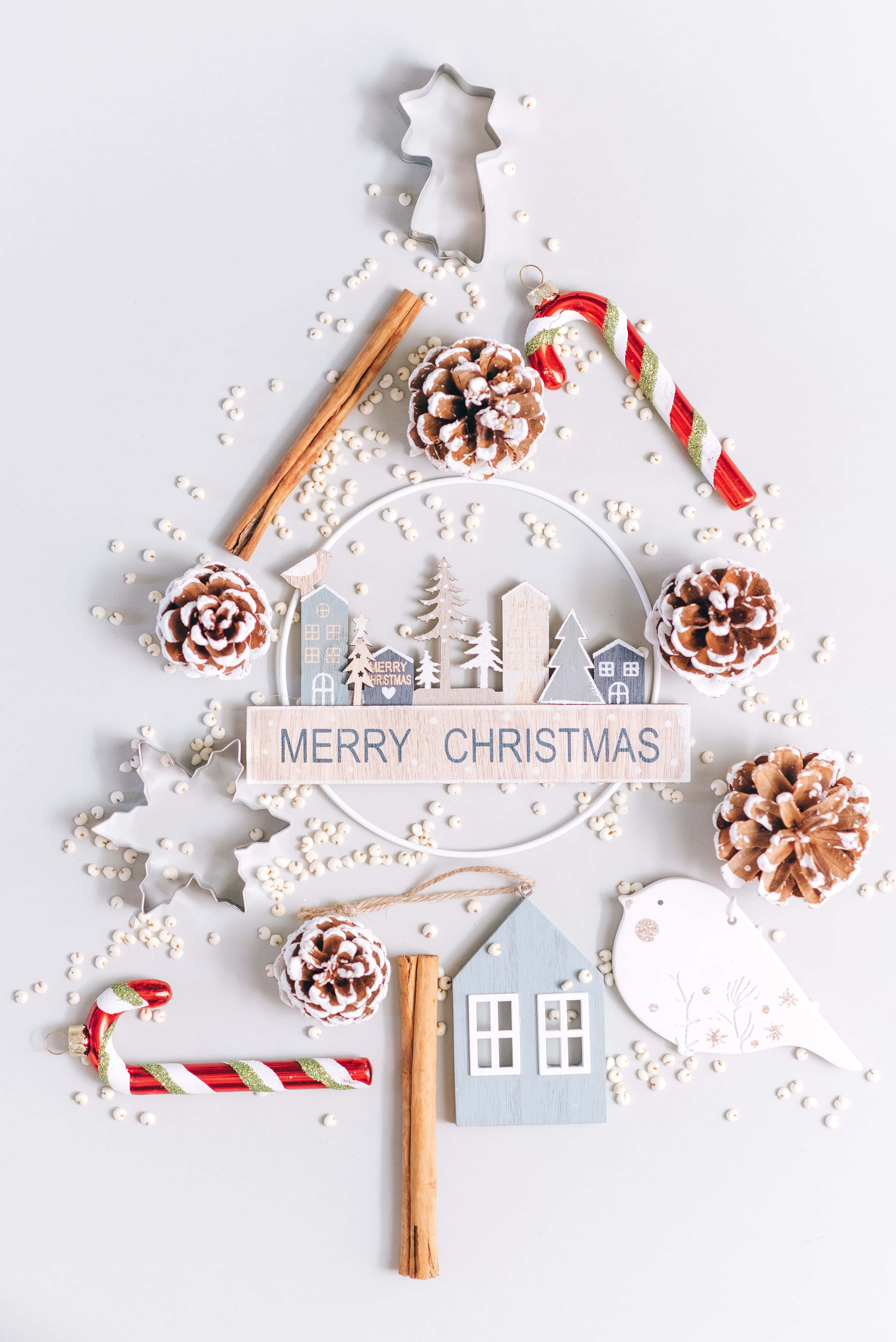 Christmas Cookie 桌布 壁紙 — 一個由松果、肉桂棒、拐杖糖和一個被白色珠子包圍的「聖誕快樂」標誌製成的平鋪聖誕樹。