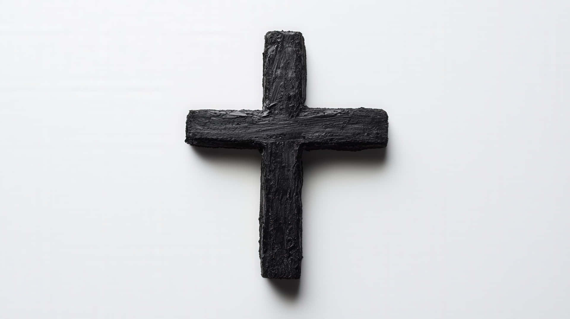Black Wooden Cross on White Background 壁紙 — 一個由燒焦木材製成的粗糙紋理黑色十字架，居中放置在純白色背景上。