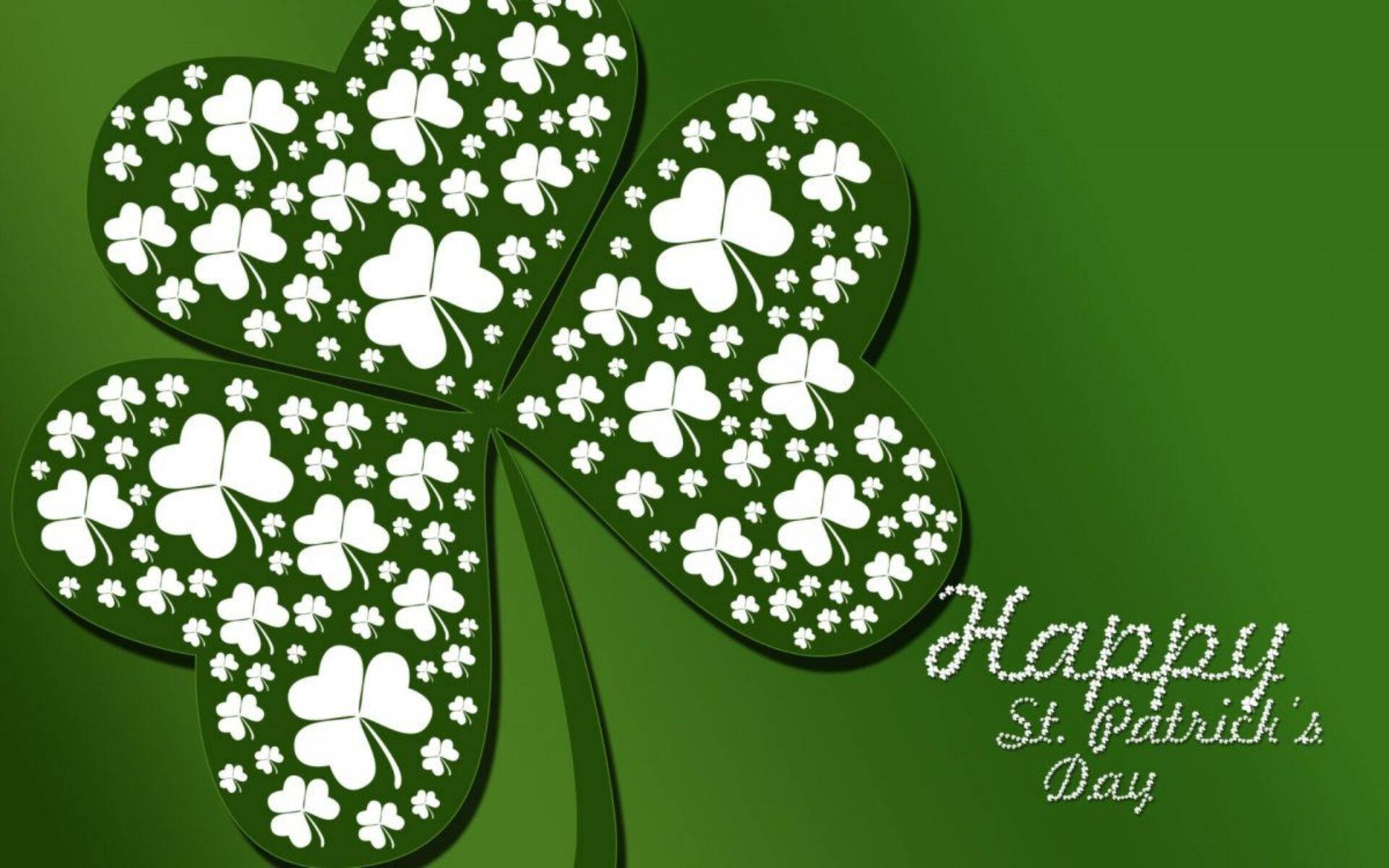 St Patrick's Day 桌布 壁紙 — 一個由白色三葉草組成的大型綠色四葉草，位於純綠色背景上，並帶有「Happy St. Patrick's Day」文字。