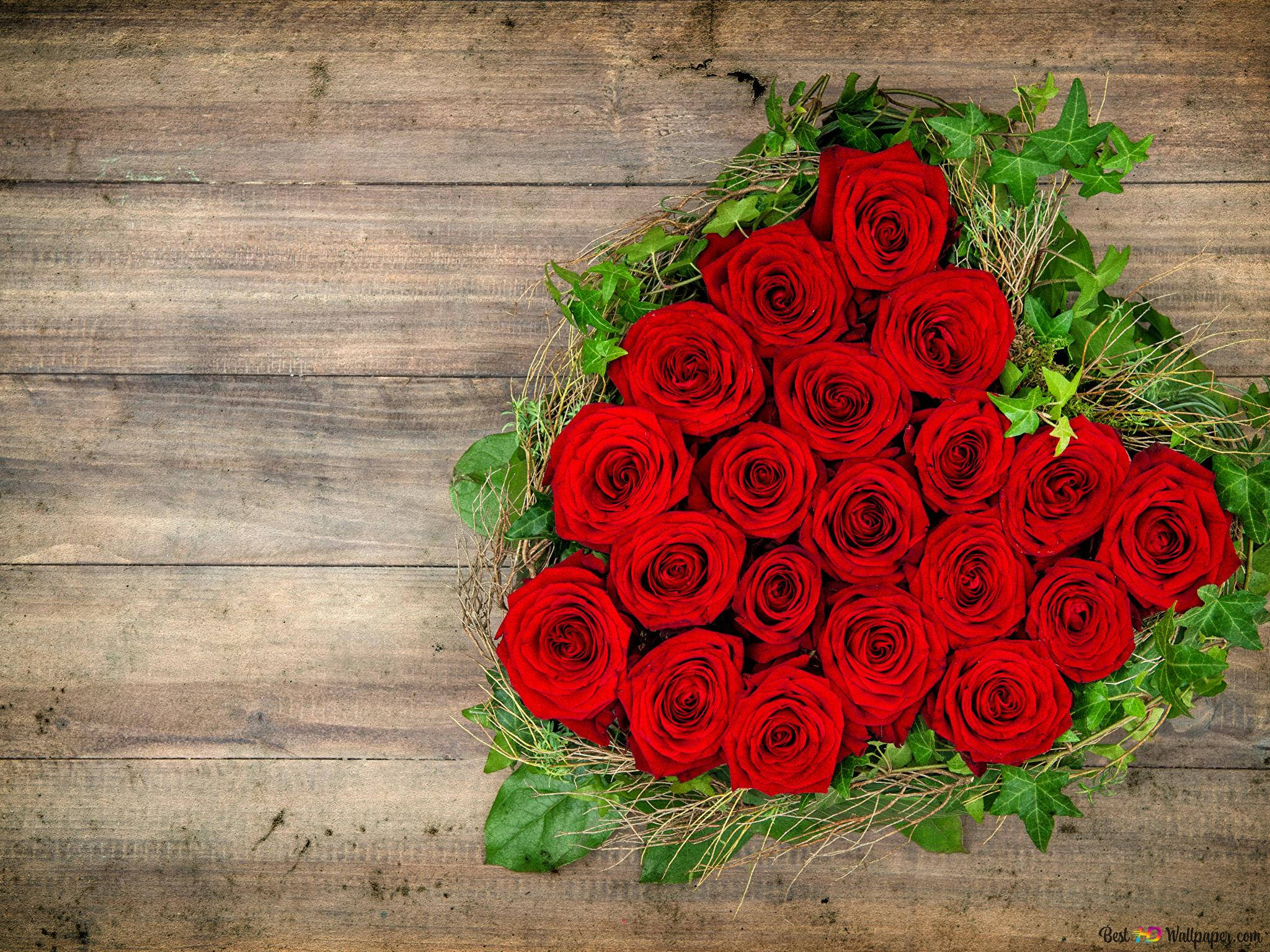 Red Roses 桌布 壁紙 — 一個由鮮豔紅玫瑰和綠色常春藤組成的心形佈置，放置在質樸風化的木質表面上。