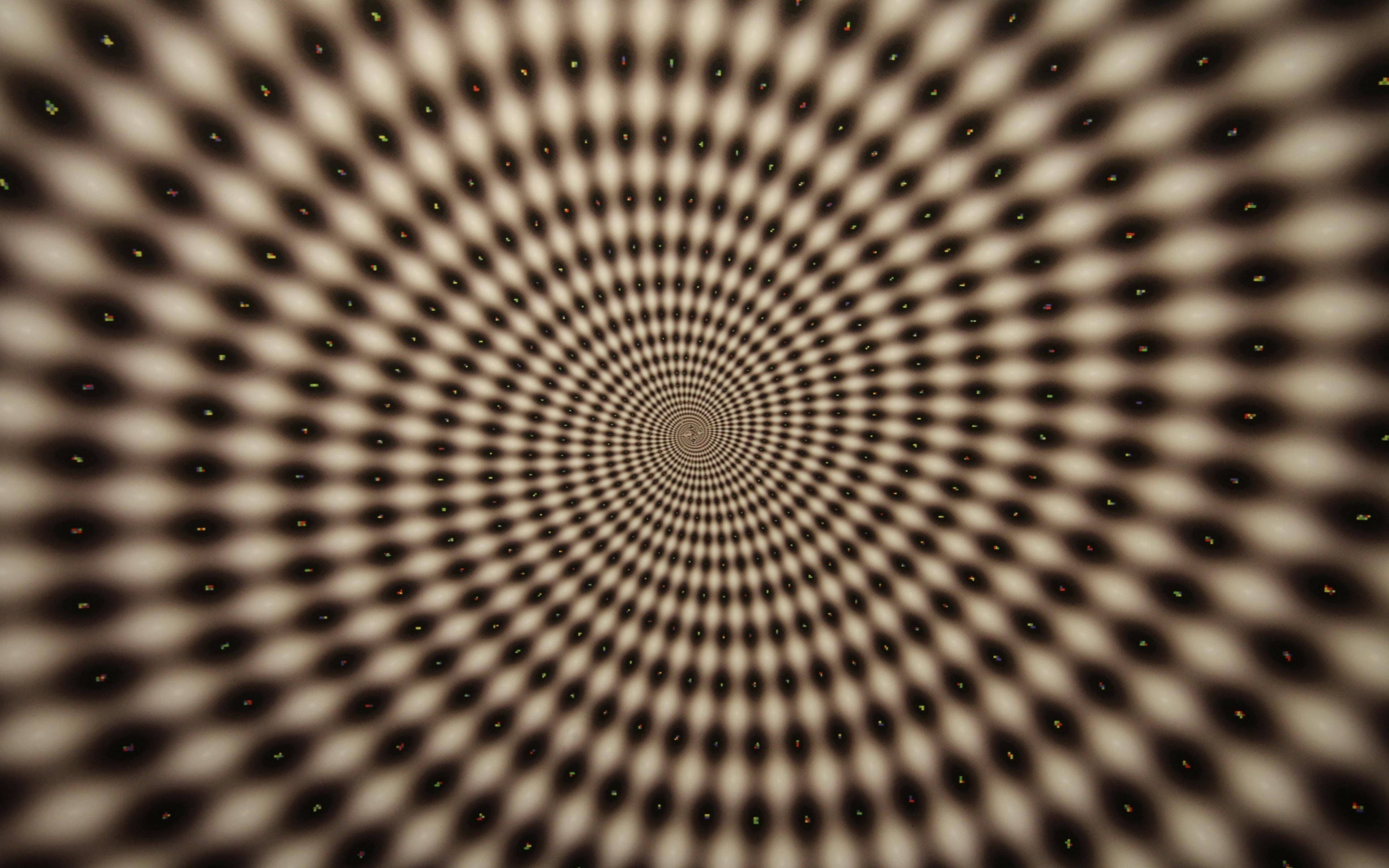 Spiral 桌布 壁紙 — 一個由黑色和米色圓點匯聚成消失點的催眠放射狀圖案。