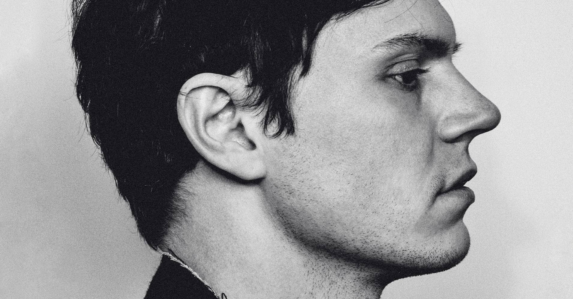 Tate Langdon 桌布 壁紙 — 一個男人側面的黑白特寫肖像，背景為純色。