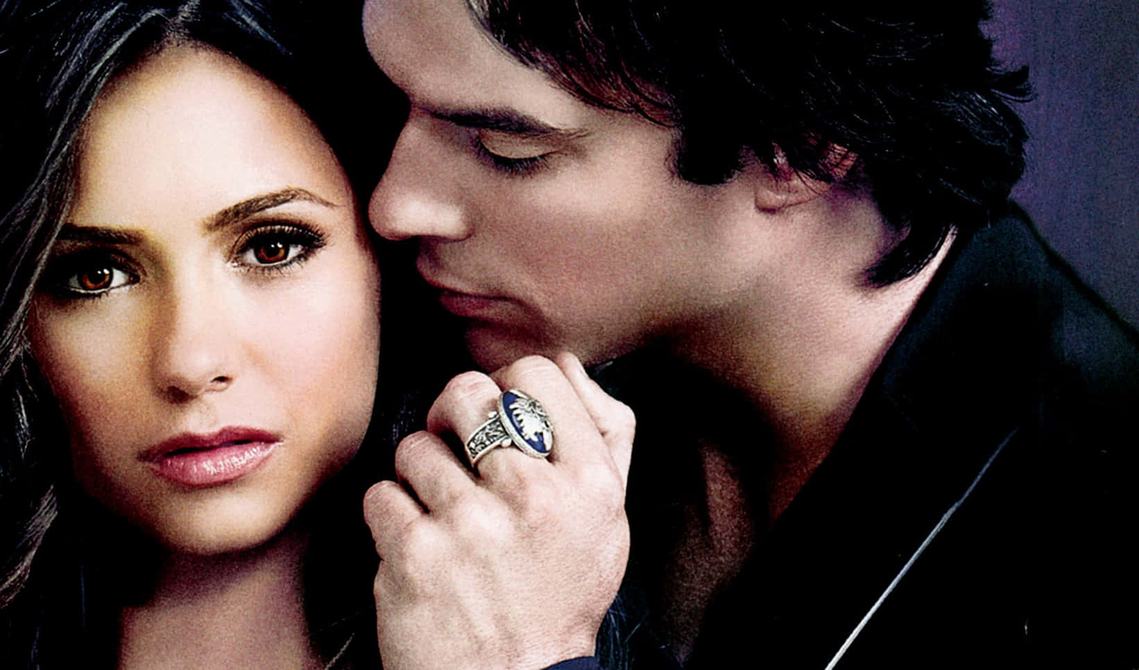 Vampire Diaries Desktop 桌布 壁紙 — 一個男人在一個女人耳邊低語，她凝視前方，他的手握著她的手，戴著一個華麗的大戒指。