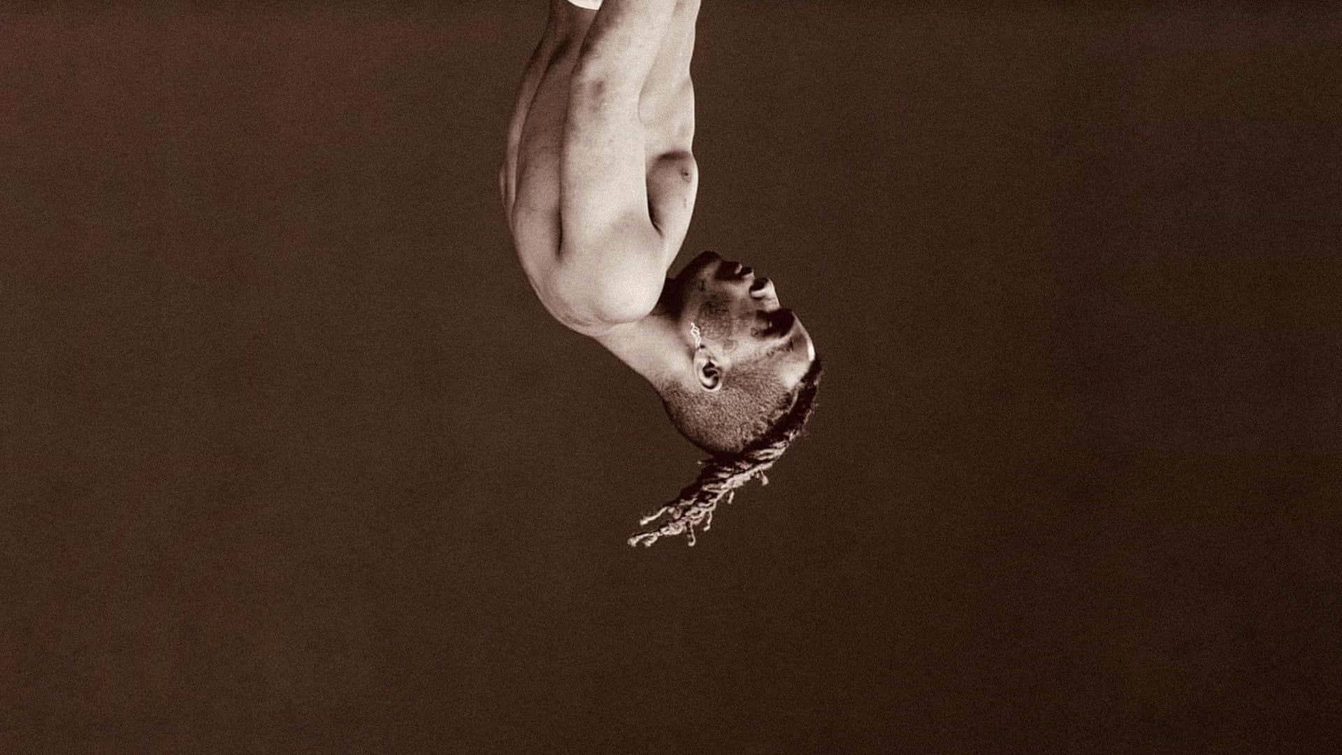 XXXTENTACION 桌布 壁紙 — 一個男人在復古色調的攝影棚中倒掛，帶有戲劇性的燈光和極簡背景。