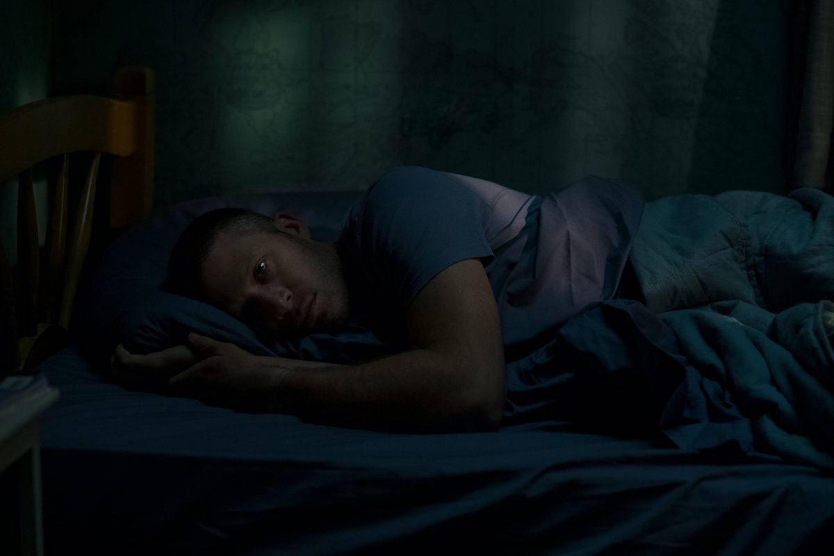 Midnight 桌布 壁紙 — 一個男人在昏暗的藍色燈光下躺在床上醒著，眼睛睜開，向上凝視，度過一個安靜無眠的夜晚。