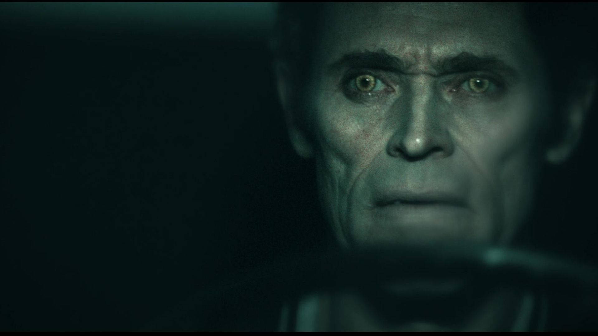 Willem Dafoe 桌布 壁紙 — 一個男人在昏暗綠光中緊繃臉部的特寫，眼睛閃爍著詭異的專注。
