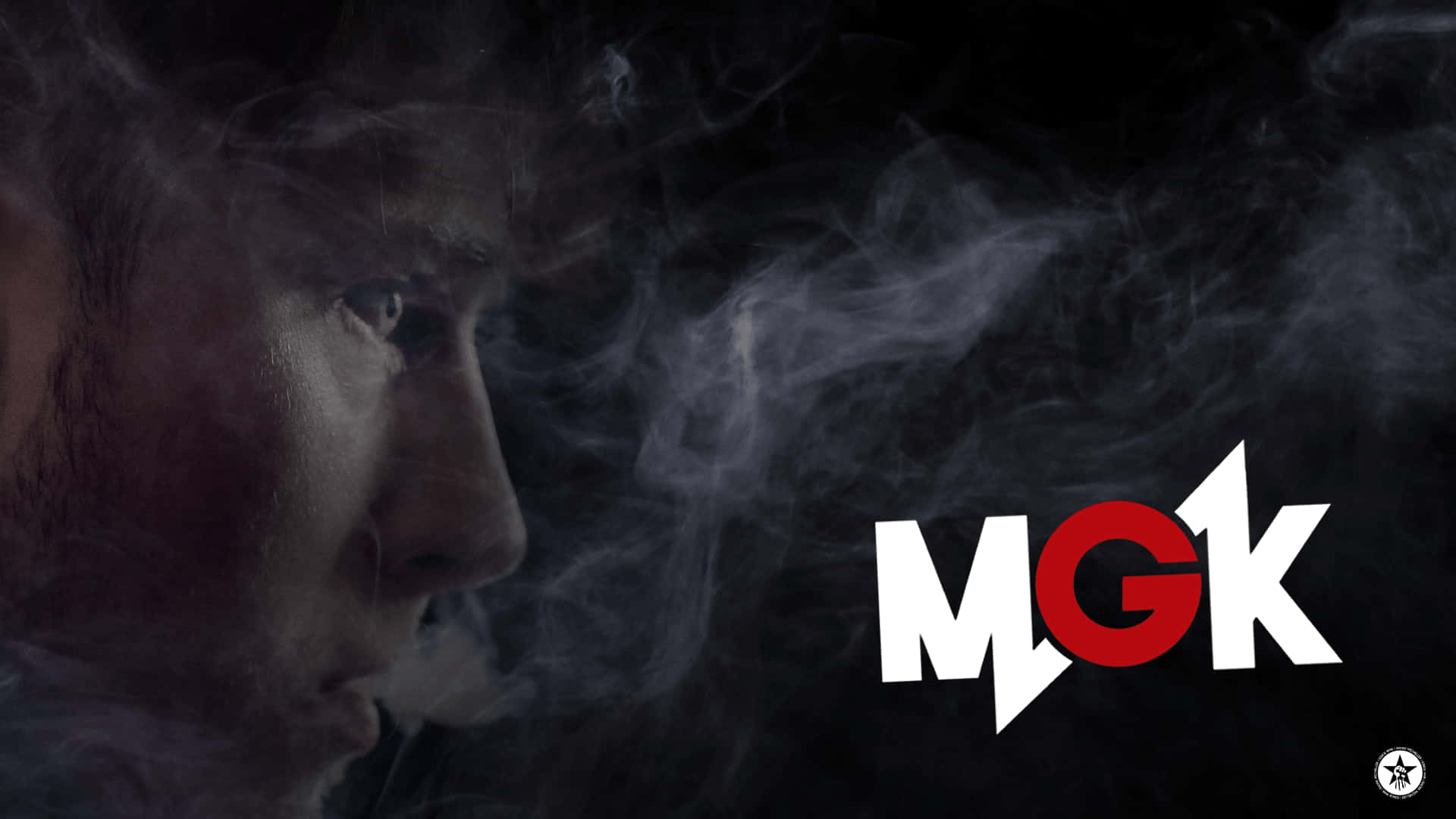 mgk 桌布 壁紙 — 一個男人在深色背景下呼出煙霧，帶有醒目的紅白MGK標誌。