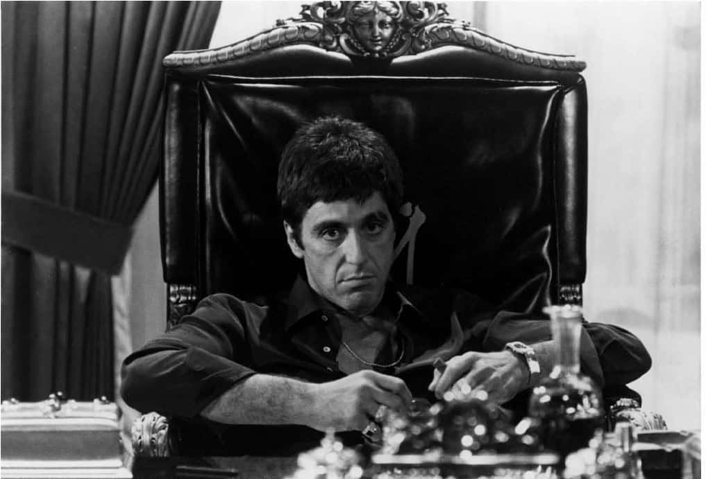 Scarface Desktop 桌布 壁紙 — 一個男人坐在華麗的王座椅上，緊握著一枚棋子，在鮮明的黑白場景中凝視著。