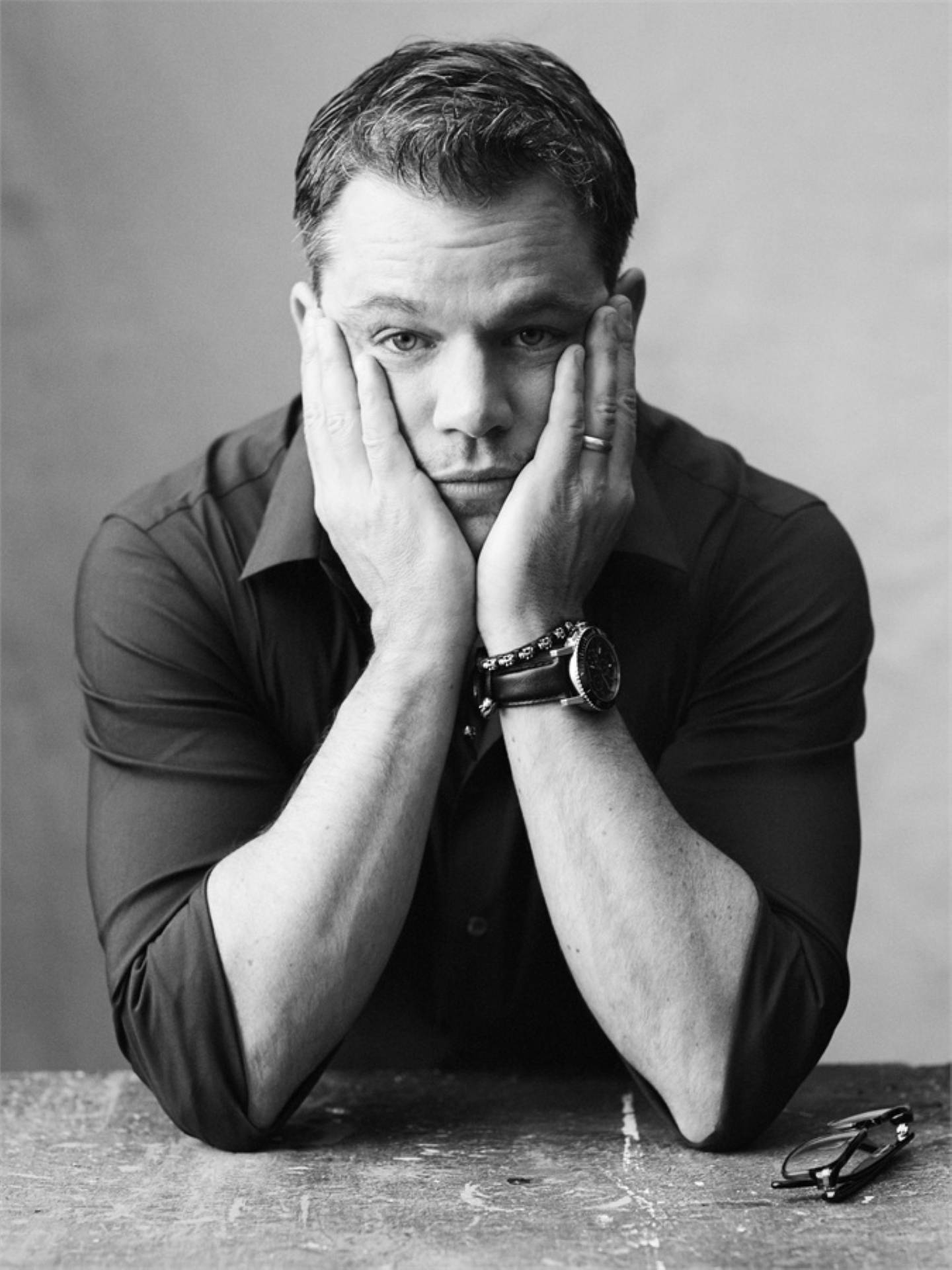 Matt Damon 桌布 壁紙 — 一個男人將下巴擱在手上，在黑白攝影棚肖像中專注地凝視鏡頭。
