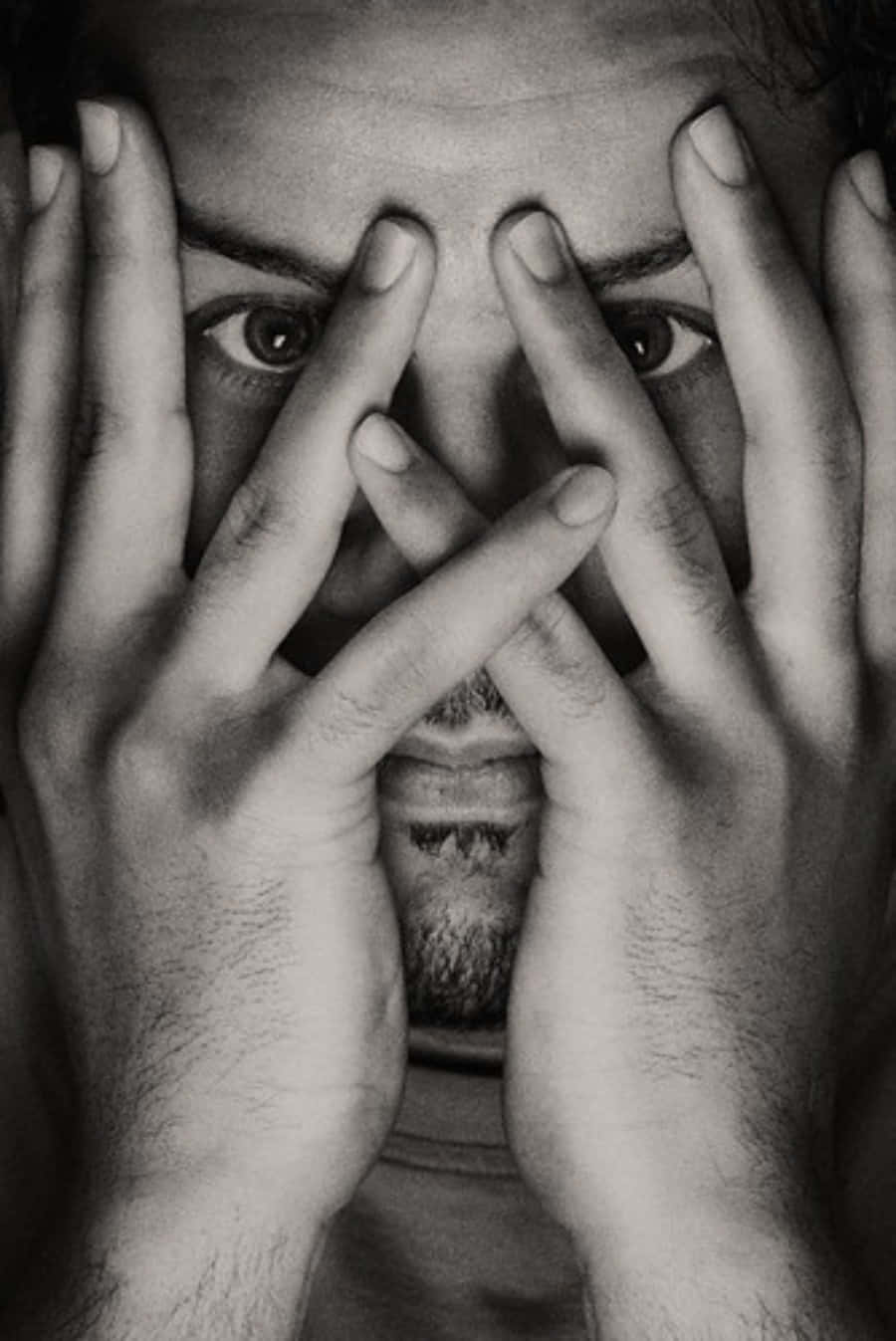 hands 桌布 壁紙 — 一個男人強烈的眼睛透過他交叉的手指在鮮明的黑白肖像中凝視。
