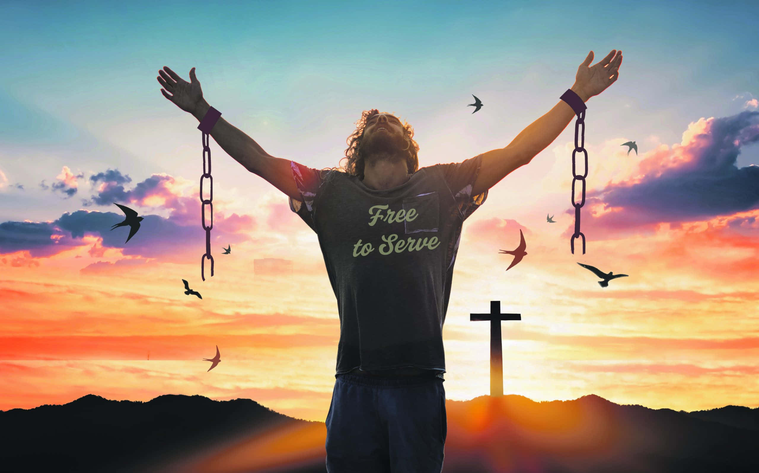 Freedom 桌布 壁紙 — 一個男人手腕上的鎖鏈掉落，舉起雙臂，背景是充滿活力的日落天空，遠處有十字架和鳥兒。