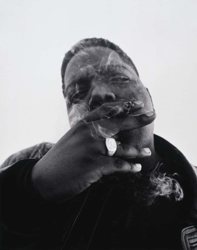 Rappers 桌布 壁紙 — 一個男人抽雪茄的黑白肖像，煙霧在他臉龐縈繞，背景簡潔。