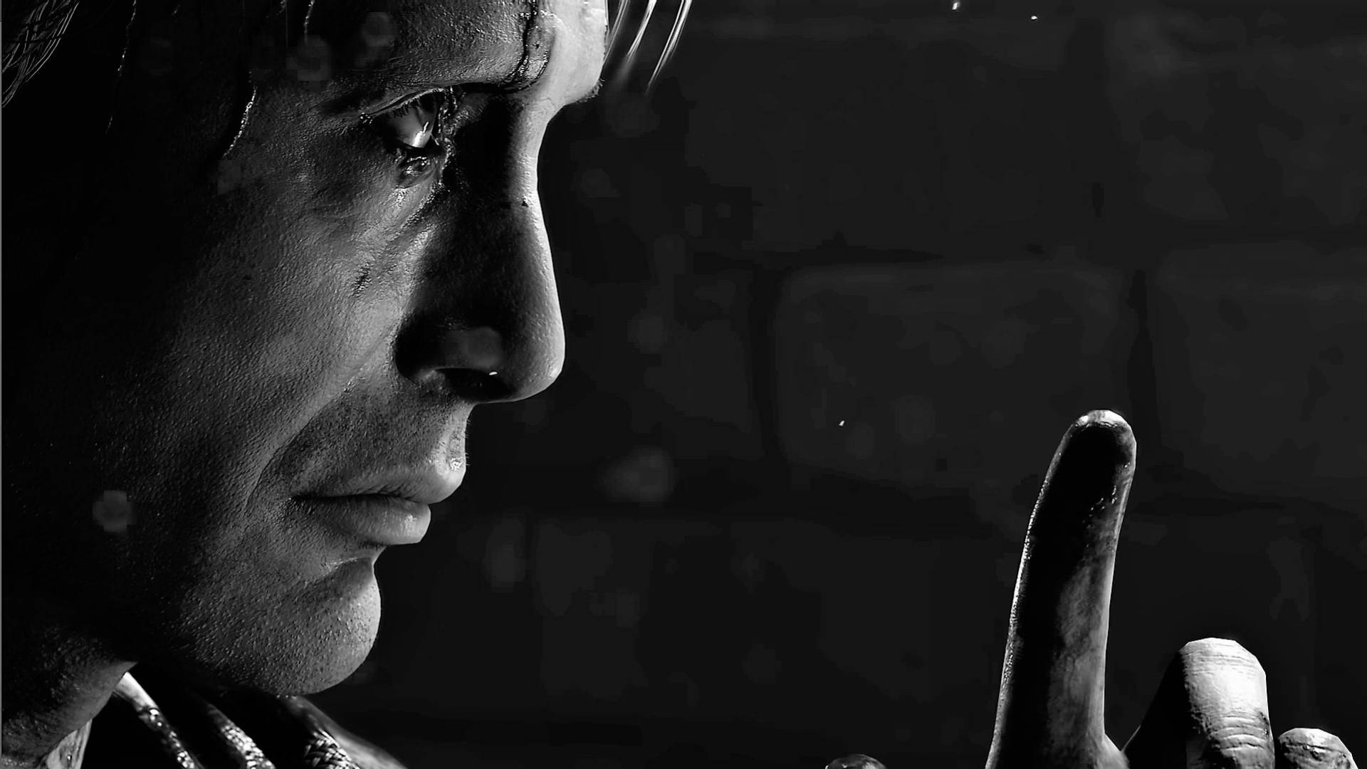 Mads Mikkelsen 桌布 壁紙 — 一個男人淚流滿面的側面黑白特寫，他的手指舉起，做出挑釁的姿勢，背景是深色磚牆。