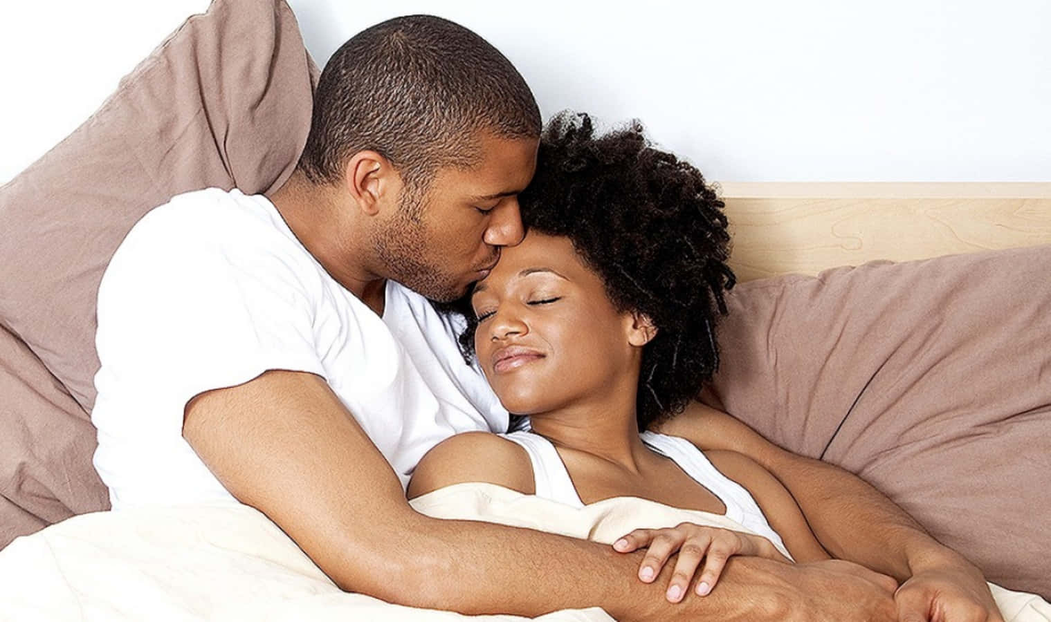 Cuddle 桌布 壁紙 — 一個男人溫柔地親吻一個熟睡女人的額頭，他們在舒適的臥室裡依偎在柔軟的床單下。